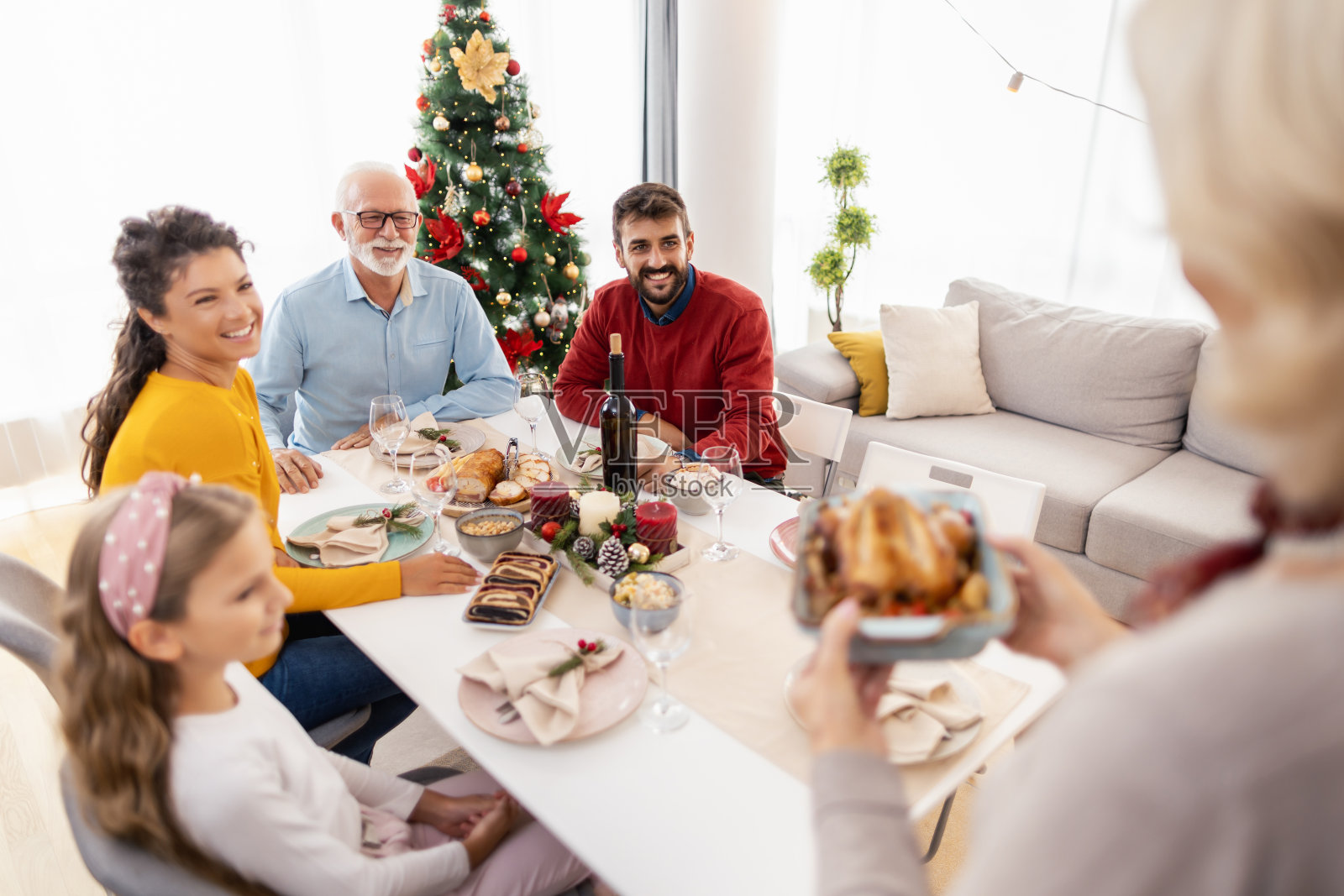 一名女子将鸡肉端上家庭圣诞晚餐的餐桌照片摄影图片