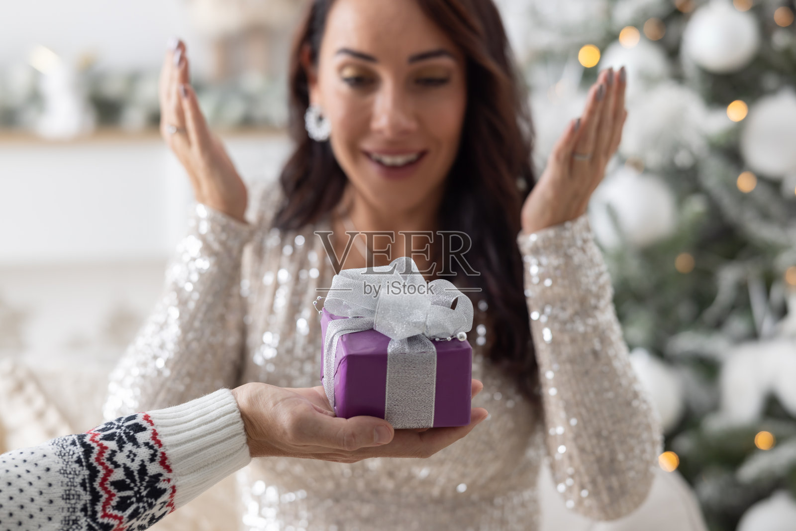 惊喜的是,当女人睁开眼睛时,男人在她面前拿着一个包装好的圣诞礼物。照片摄影图片