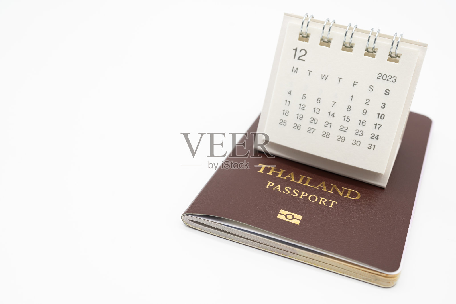 2023年12月的简易台历和护照。日历和假期的概念与护照隔离在白色背景。照片摄影图片