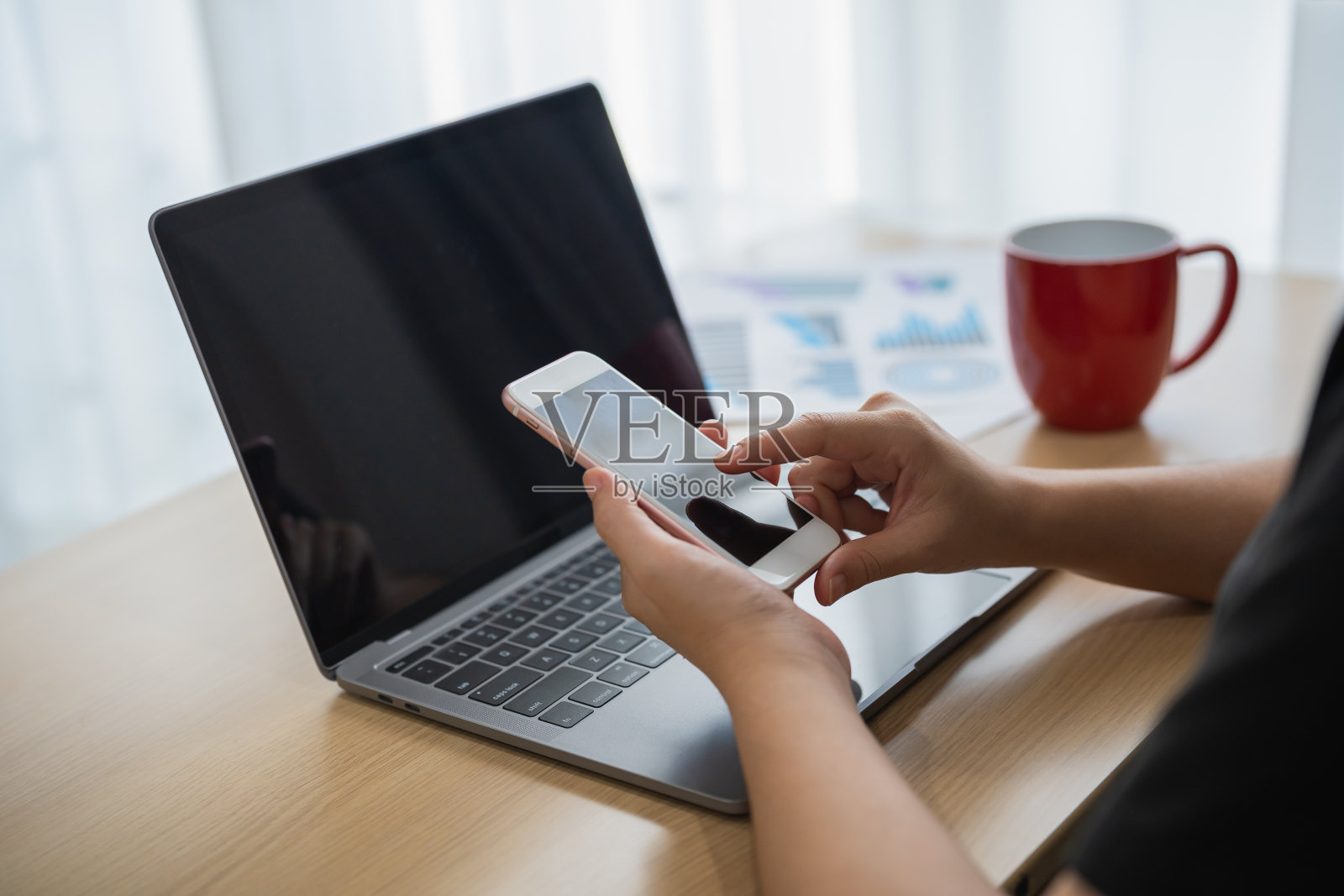 女商人把笔记本电脑放在桌子上工作后使用智能手机,女商人用手机搜索或社交媒体或网上购物或股票或加密货币。智能电话通话会议。照片摄影图片