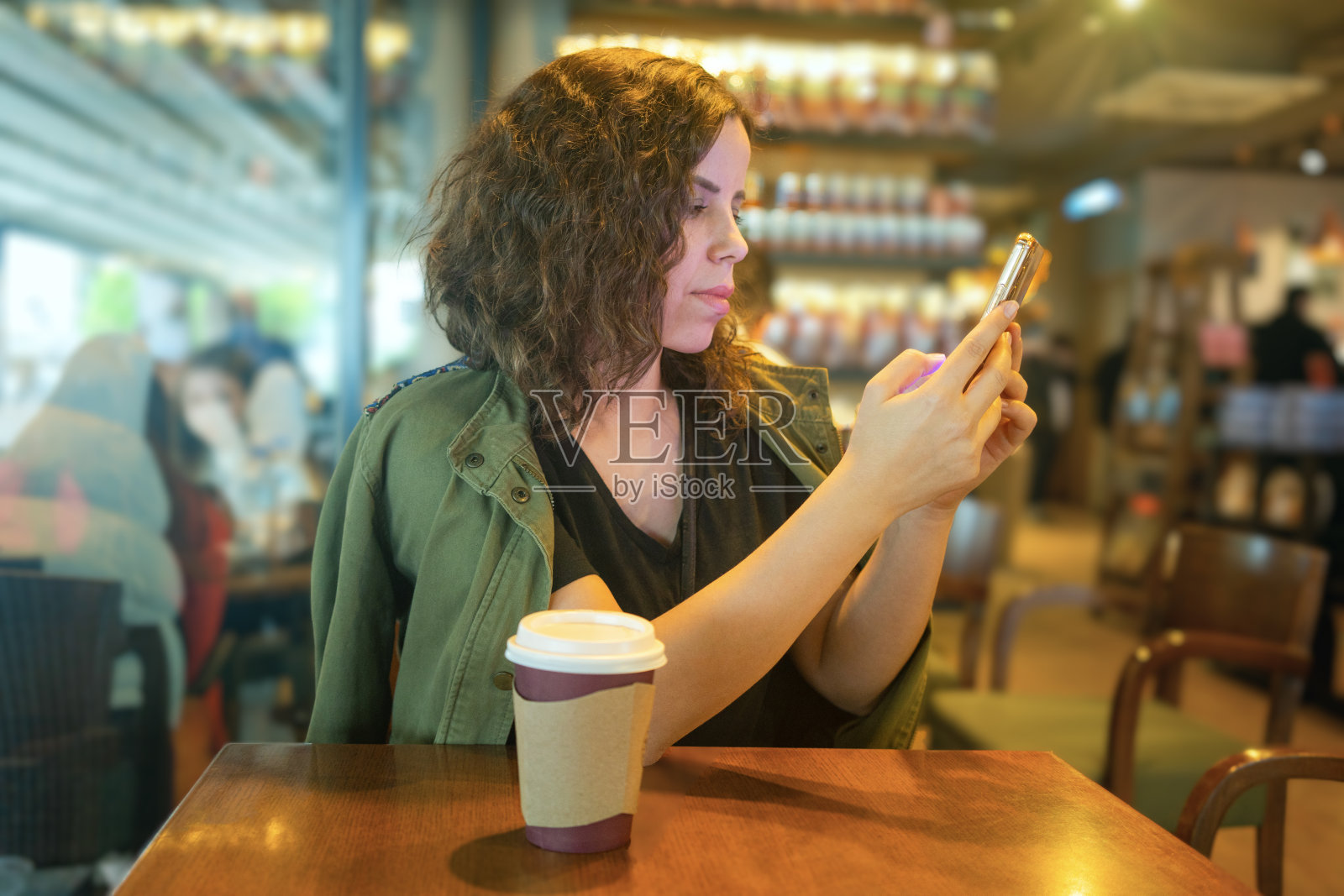 美女一边在咖啡店喝咖啡,一边用智能手机做金融工作。复古色调。照片摄影图片