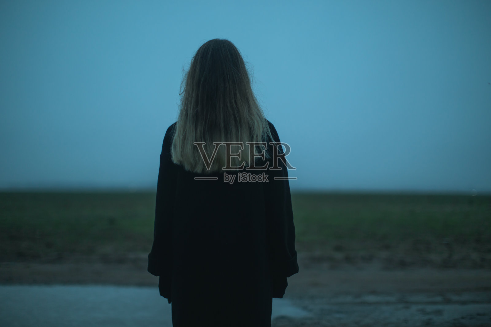 在田野上的金发女人,天空为背景照片摄影图片