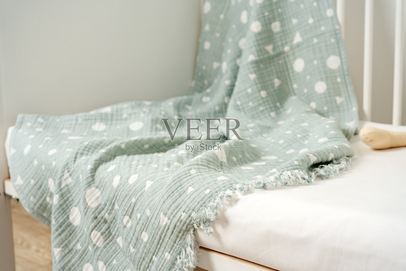 在育婴室里,孩子的床上挂着棉布婴儿毯照片摄影图片