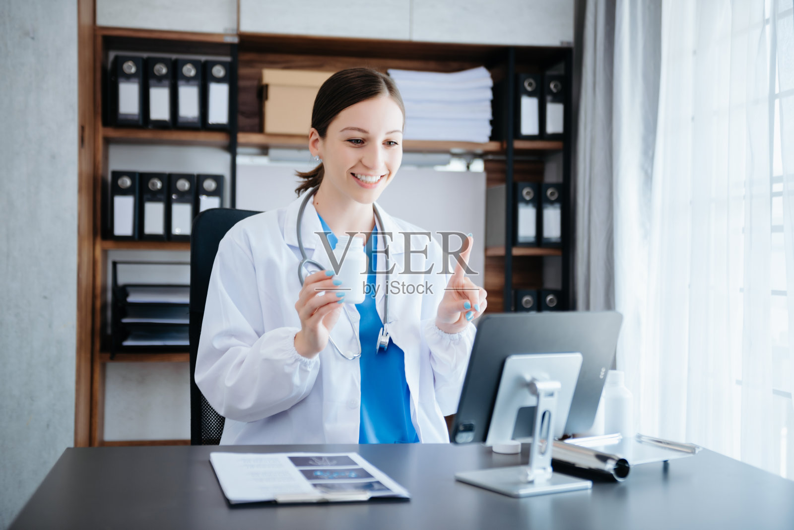 有魅力的女医生一边用笔记本电脑视频通话一边向病人解释治疗方法照片摄影图片