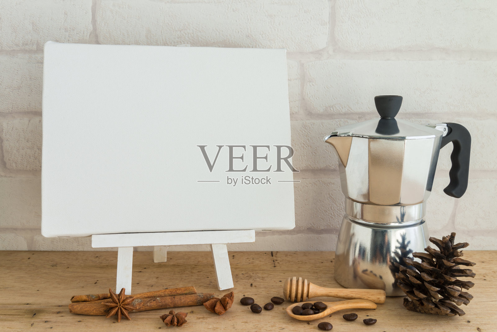 空白的白色帆布在木制画架和咖啡壶与白墙背景复制空间。照片摄影图片