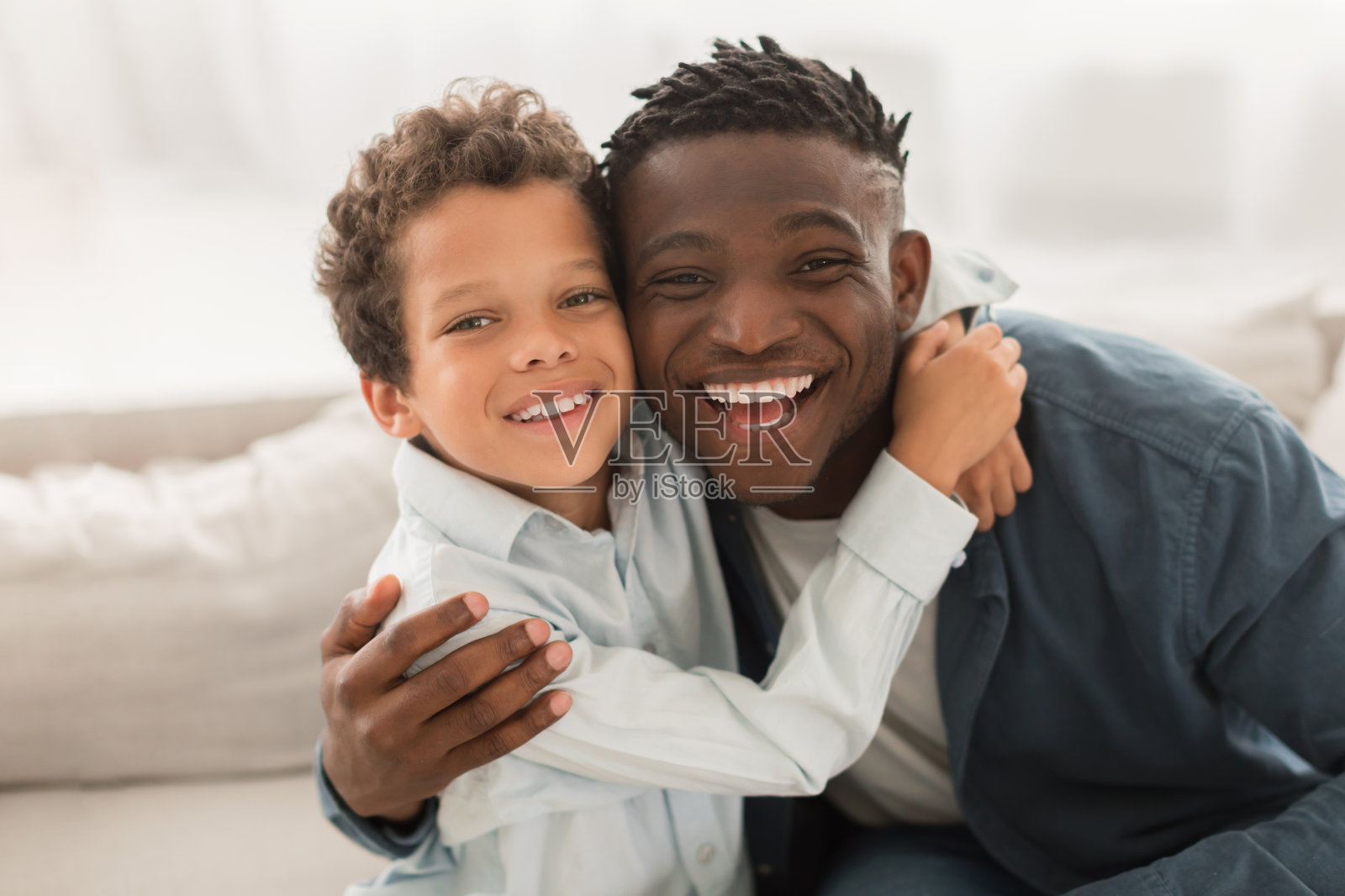 非裔美国爸爸抱着小儿子在室内看镜头照片摄影图片