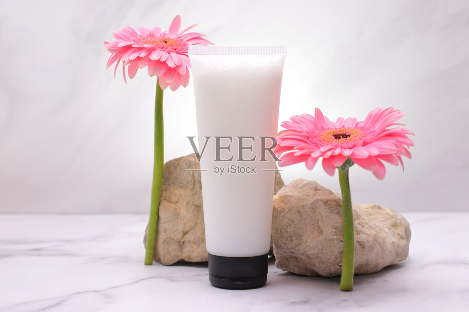 白色试管模拟护肤霜,乳液瓶模拟与粉红色的花照片摄影图片