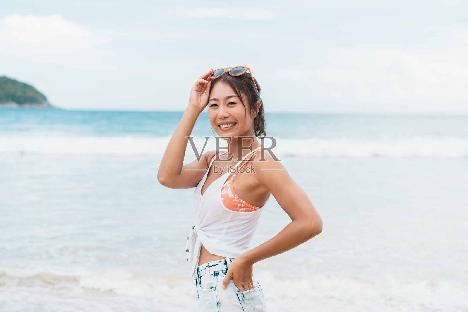 海滩上快乐微笑的美女肖像。漂亮的年轻亚洲女孩穿着休闲的衣服在明亮的天空中笑照片摄影图片