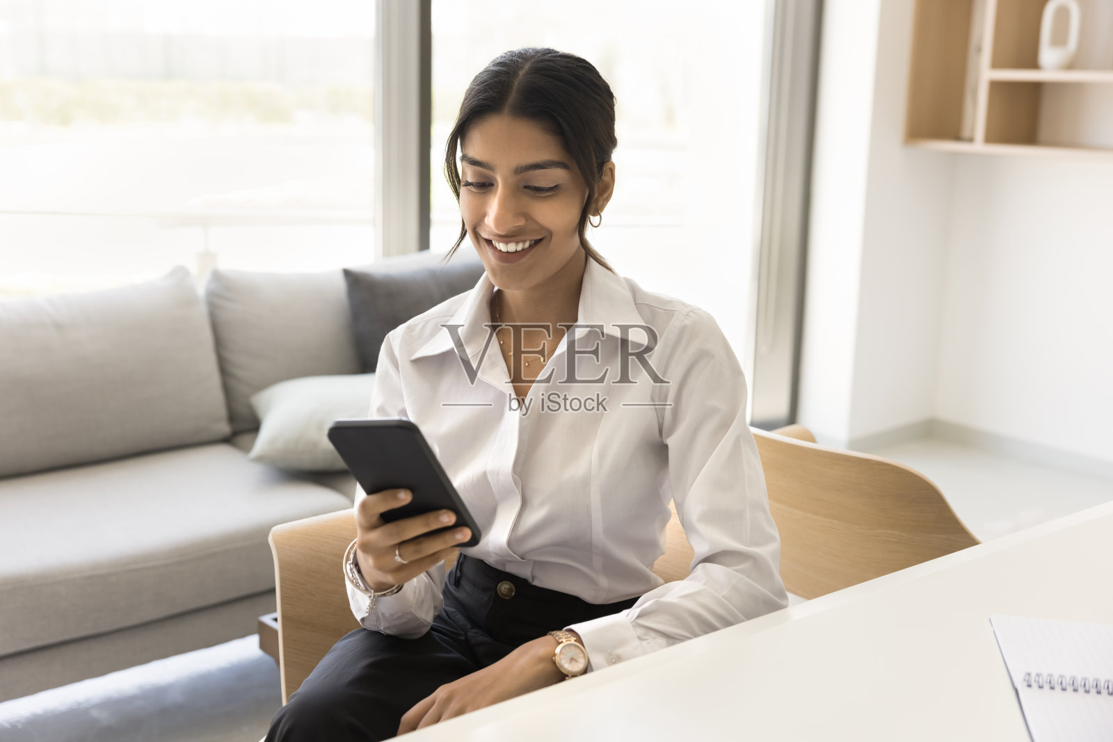 快乐的年轻漂亮的印度职业女性在手机上打字照片摄影图片