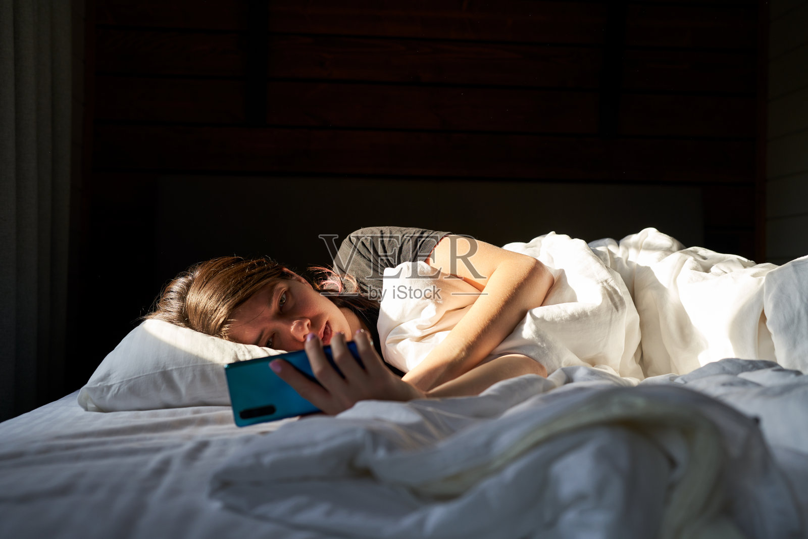 躺在床上用智能手机查看社交媒体的女人照片摄影图片