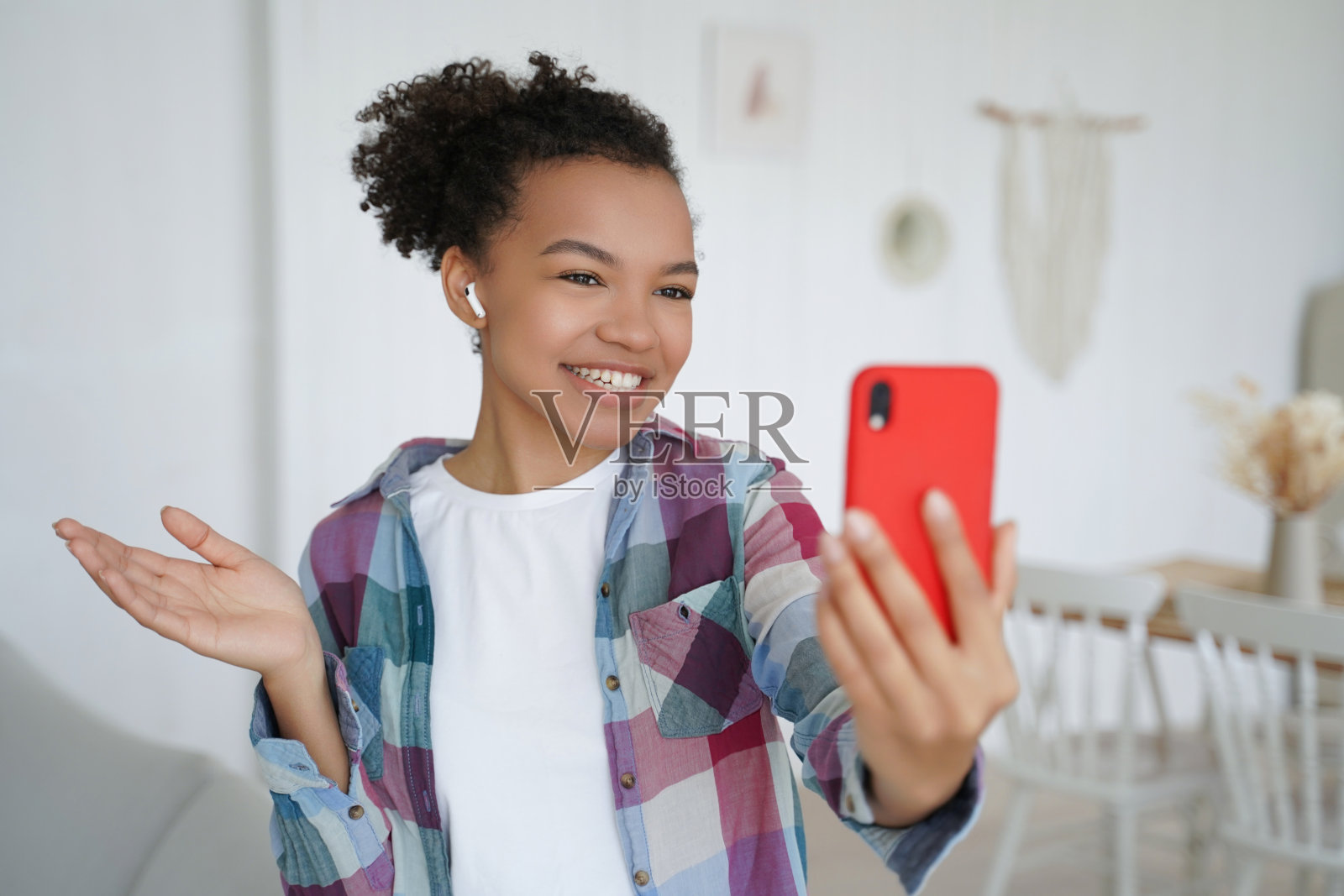 笑容灿烂的黑人女孩戴着耳机用智能手机视频通话。照片摄影图片