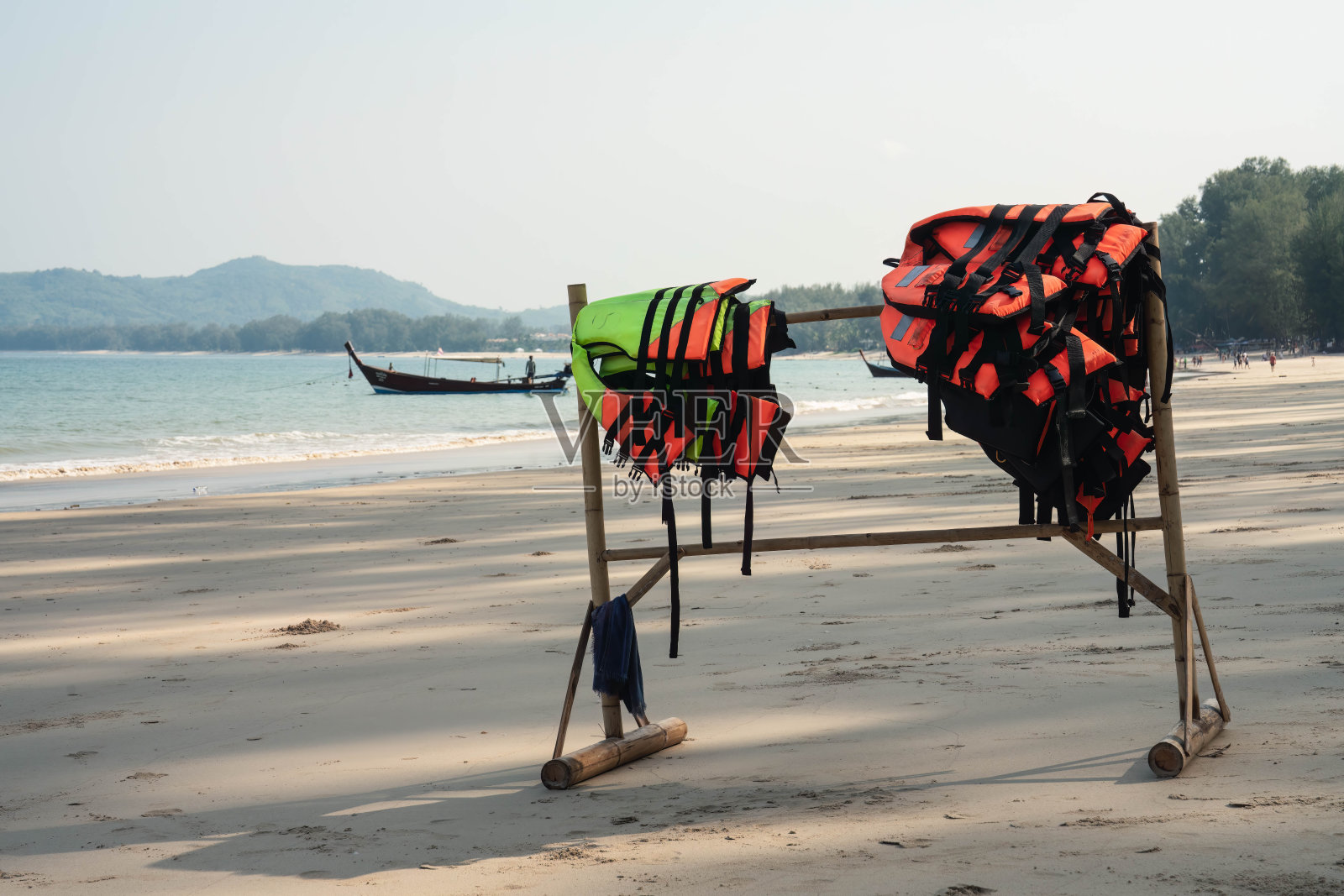 在靠近海岸线的空旷沙滩上,挂着许多安全救生衣的木制衣架,清晨,没有游客。特写照片照片摄影图片