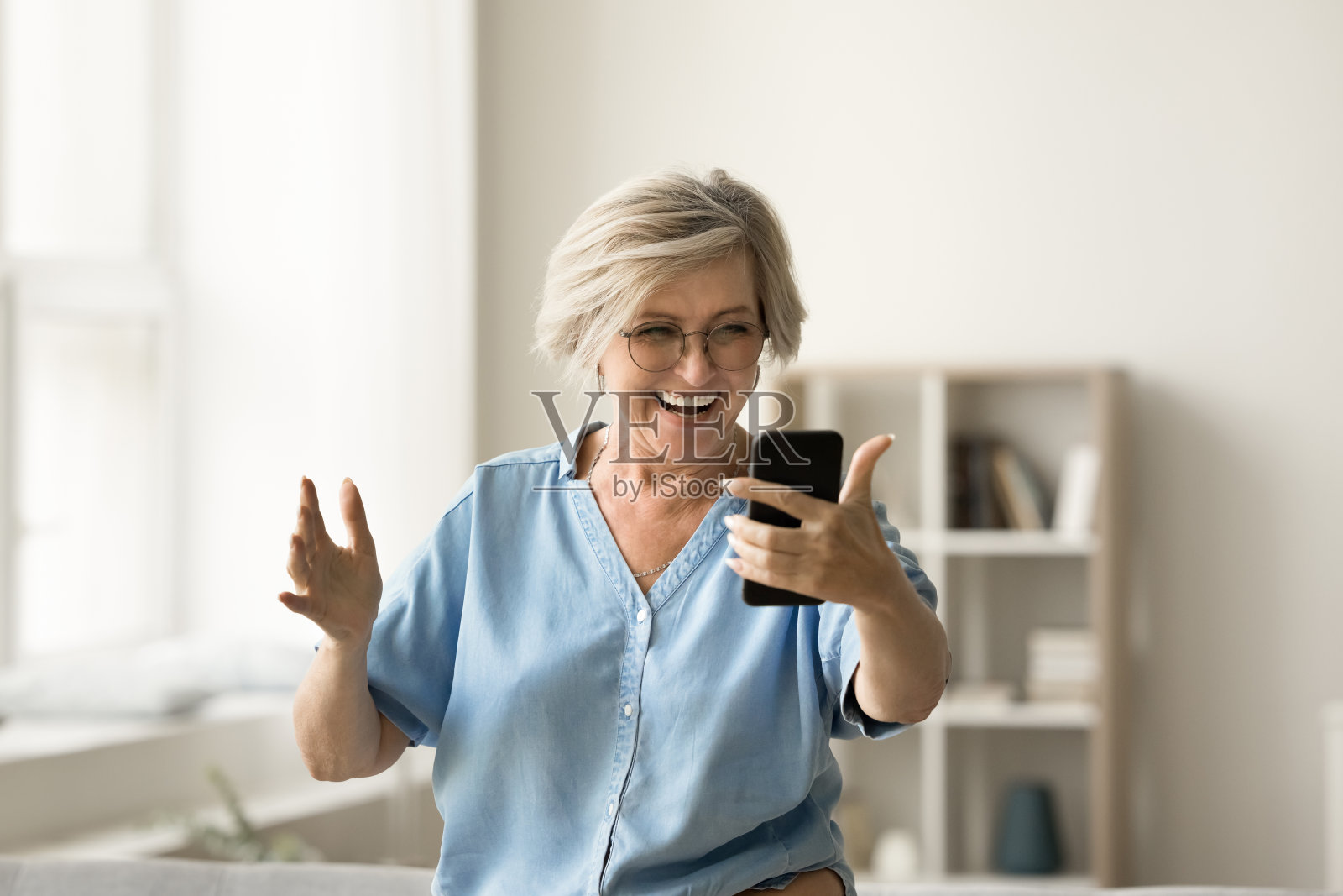 快乐的成熟老妇人用智能手机进行视频通话照片摄影图片