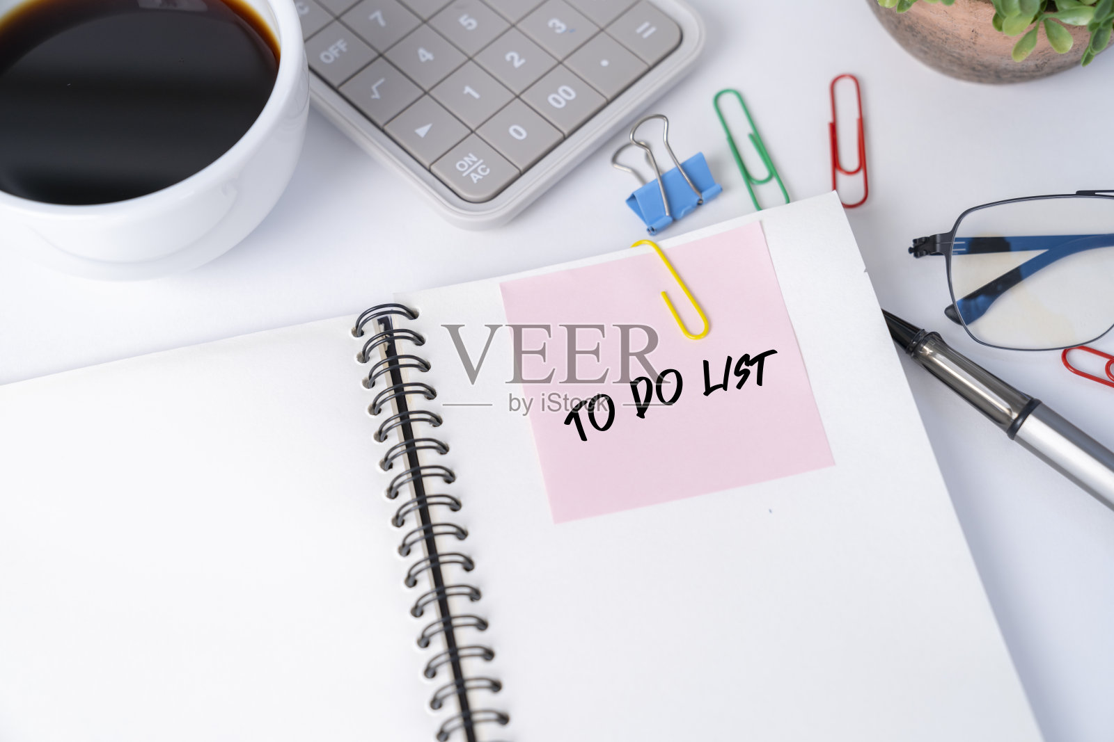 办公桌上的笔记本上贴着粉红色的贴纸。照片摄影图片