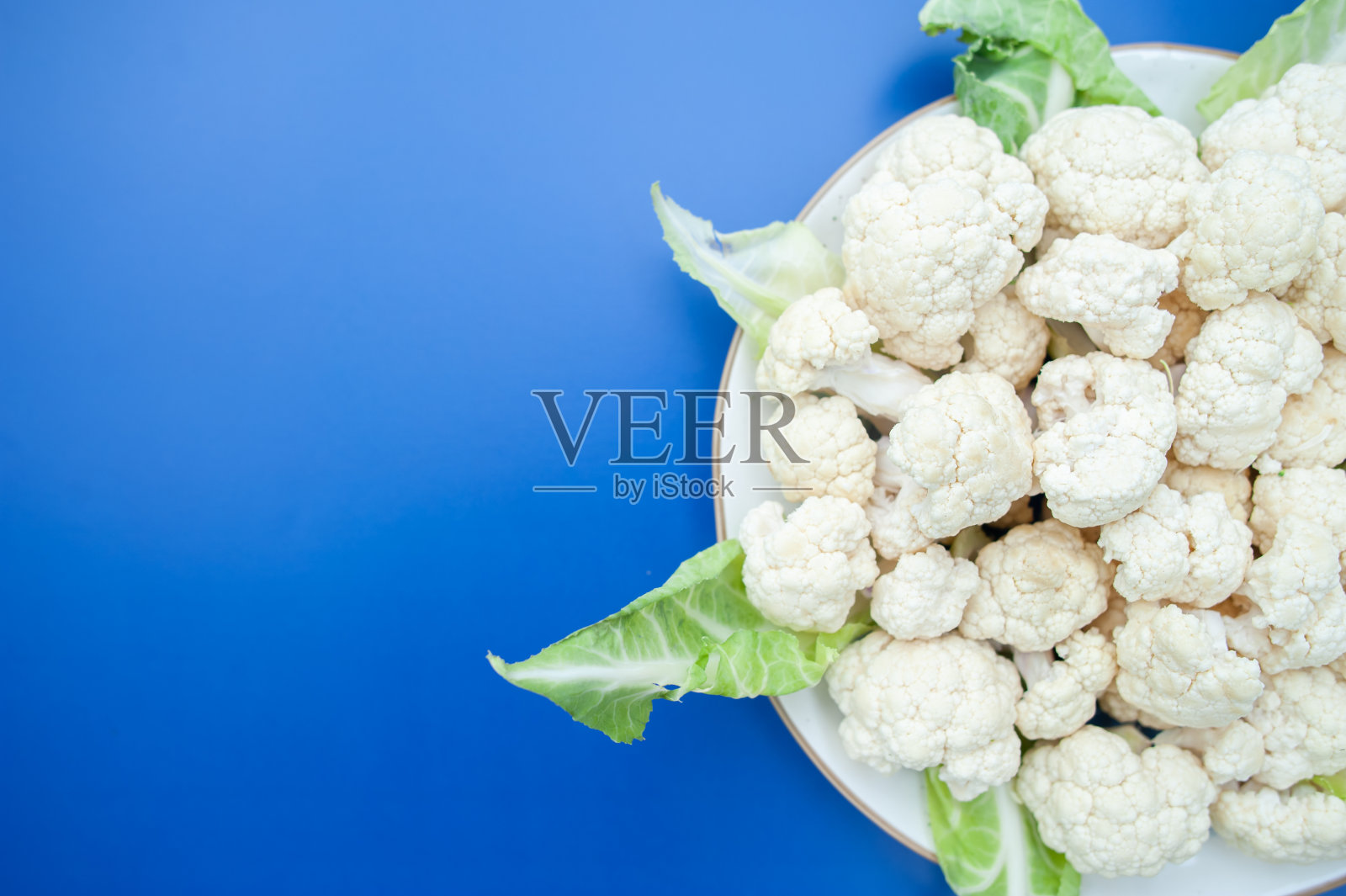 花椰菜花序特写在一个盘子上,俯视图,蓝色背景,文字的空间照片摄影图片