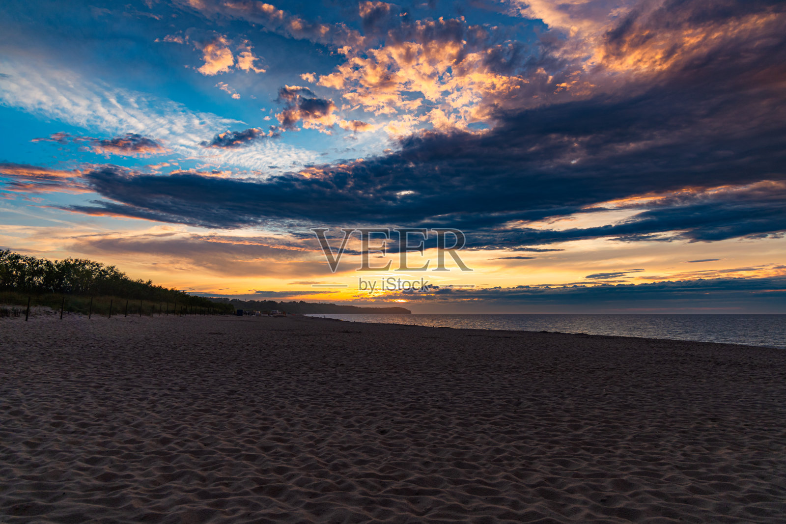 美丽的金色日落在黄金时间在海滩旁边的黑暗和寒冷的大海在夏天的风暴和雨水之后照片摄影图片