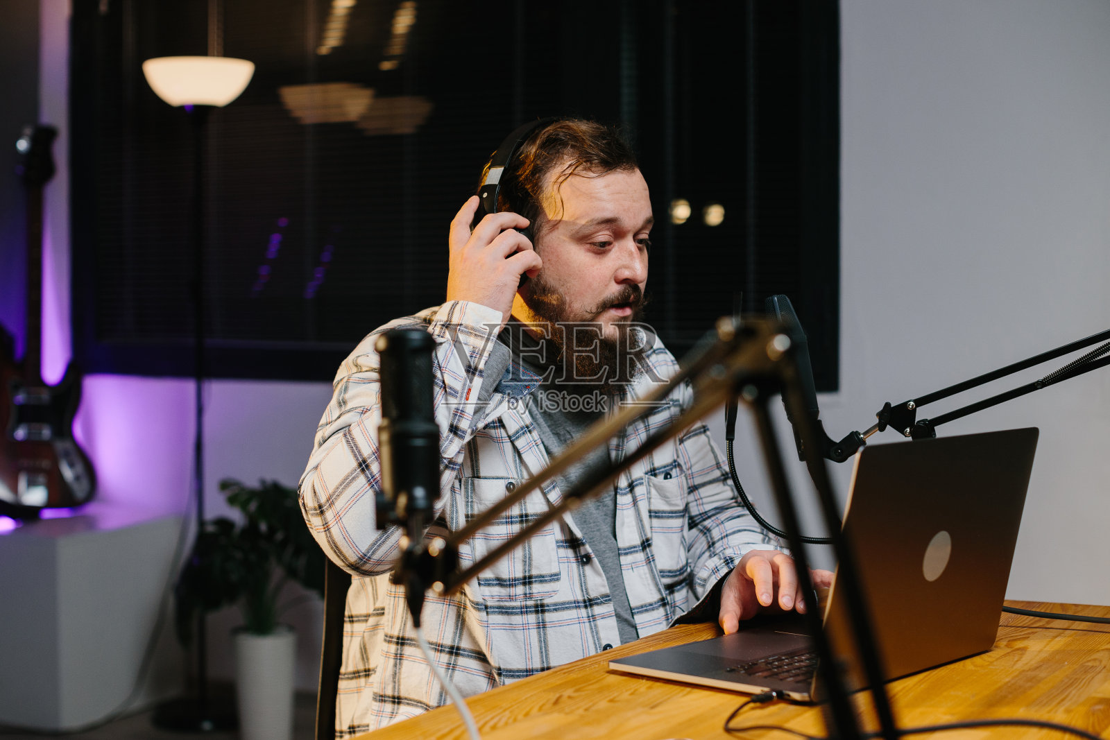 一位在线博主在直播过程中对着麦克风讲话。广播期间在演播室的电台主持人。照片摄影图片