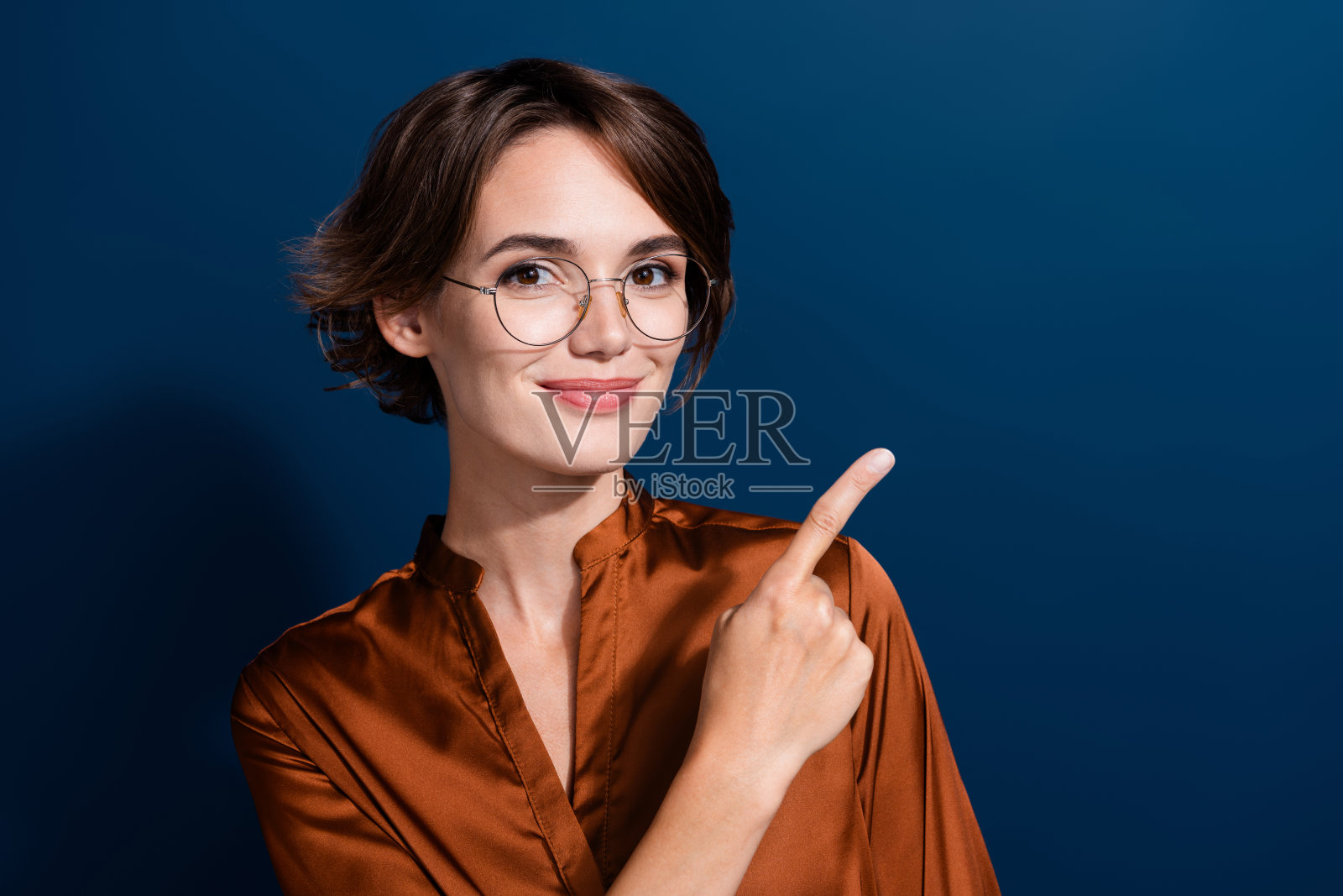 照片中可爱可爱的女士穿着时髦的衣服,手臂直接空无一物的新闻效益孤立在深蓝色的背景上照片摄影图片