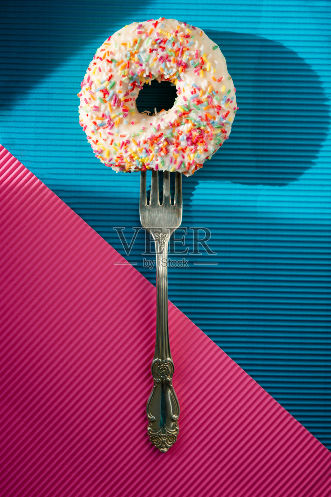 叉子上的甜甜圈在彩色背景下照片摄影图片