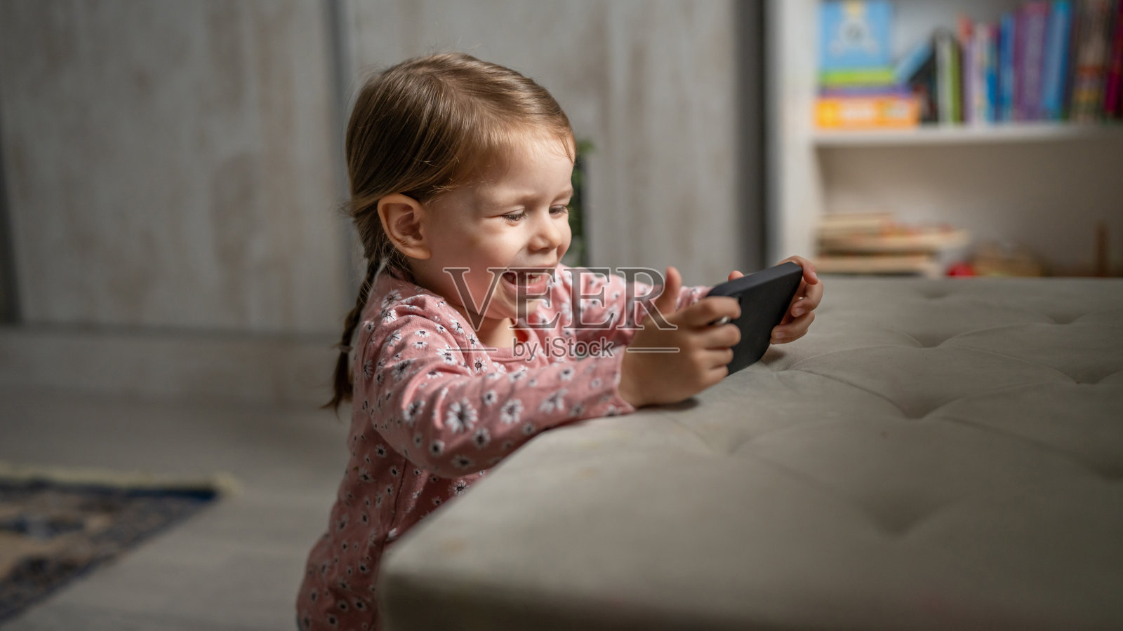 一个蹒跚学步的女孩在玩手机智能手机上的视频游戏照片摄影图片