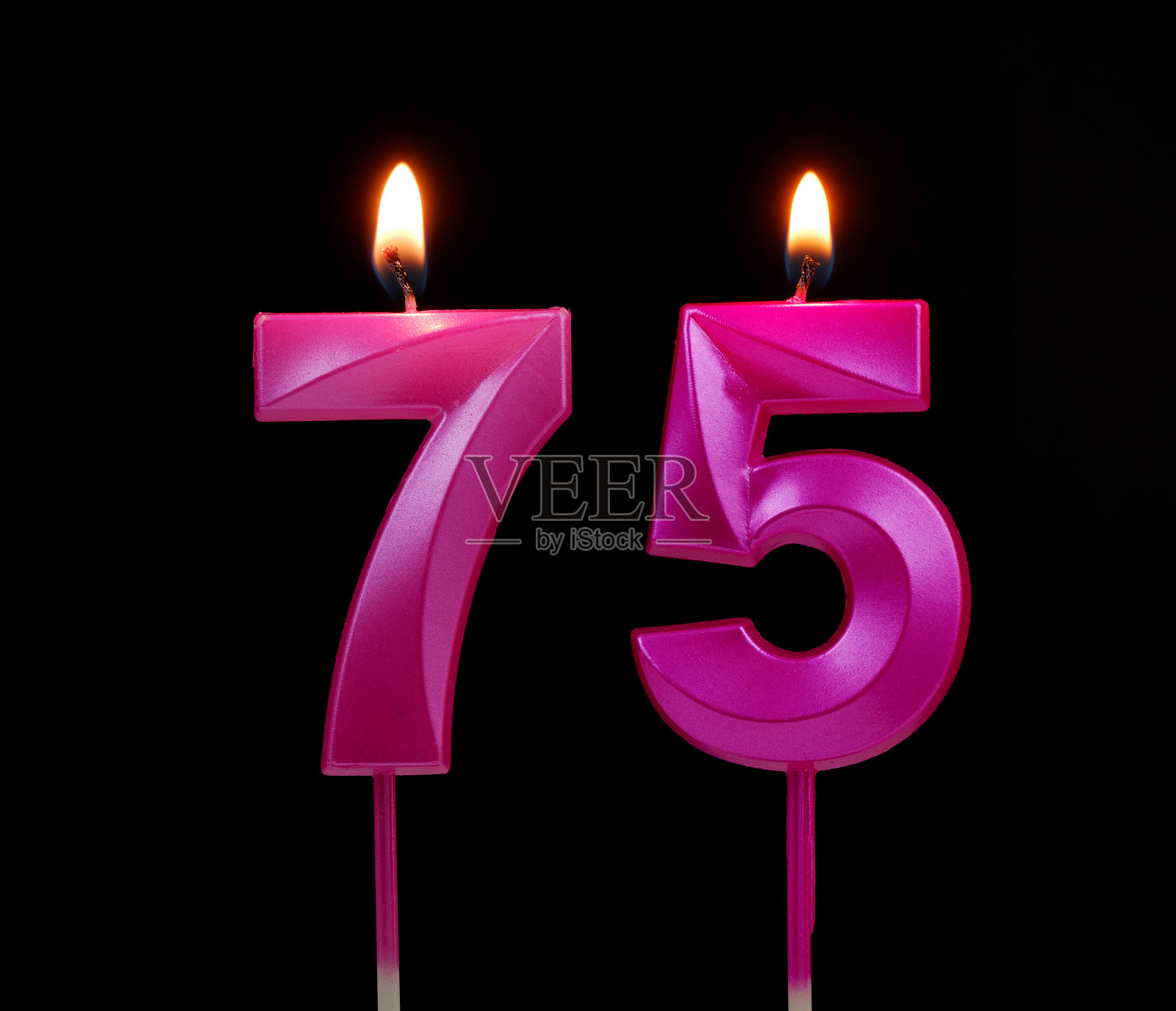粉红色生日蜡烛孤立在黑色背景,编号75照片摄影图片