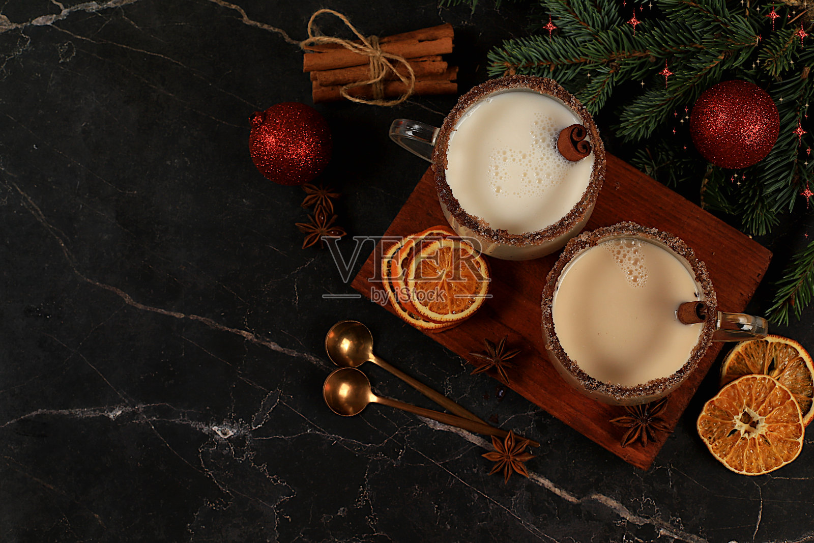 蛋奶酒与肉桂,肉豆蔻和姜牛奶饮料为圣诞和冬季假期在冷杉树枝和装饰的背景。寒季暖乳饮品,节日成分,照片摄影图片