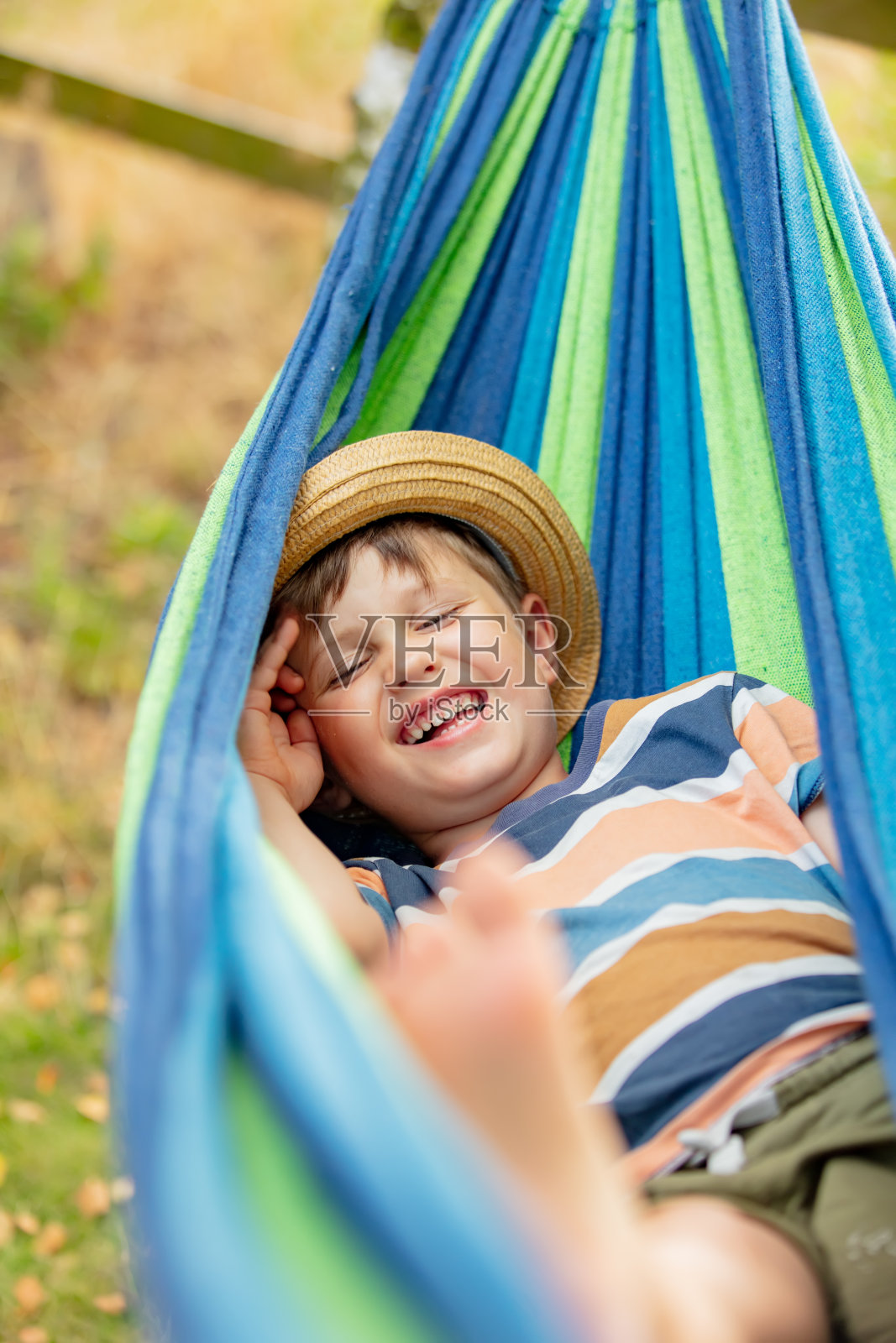 夏日花园吊床上快乐的小男孩照片摄影图片