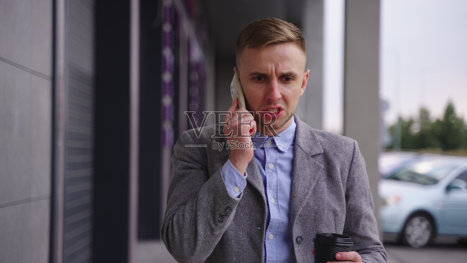 一个年轻人走在街上,一边用智能手机打电话。慢动作照片摄影图片