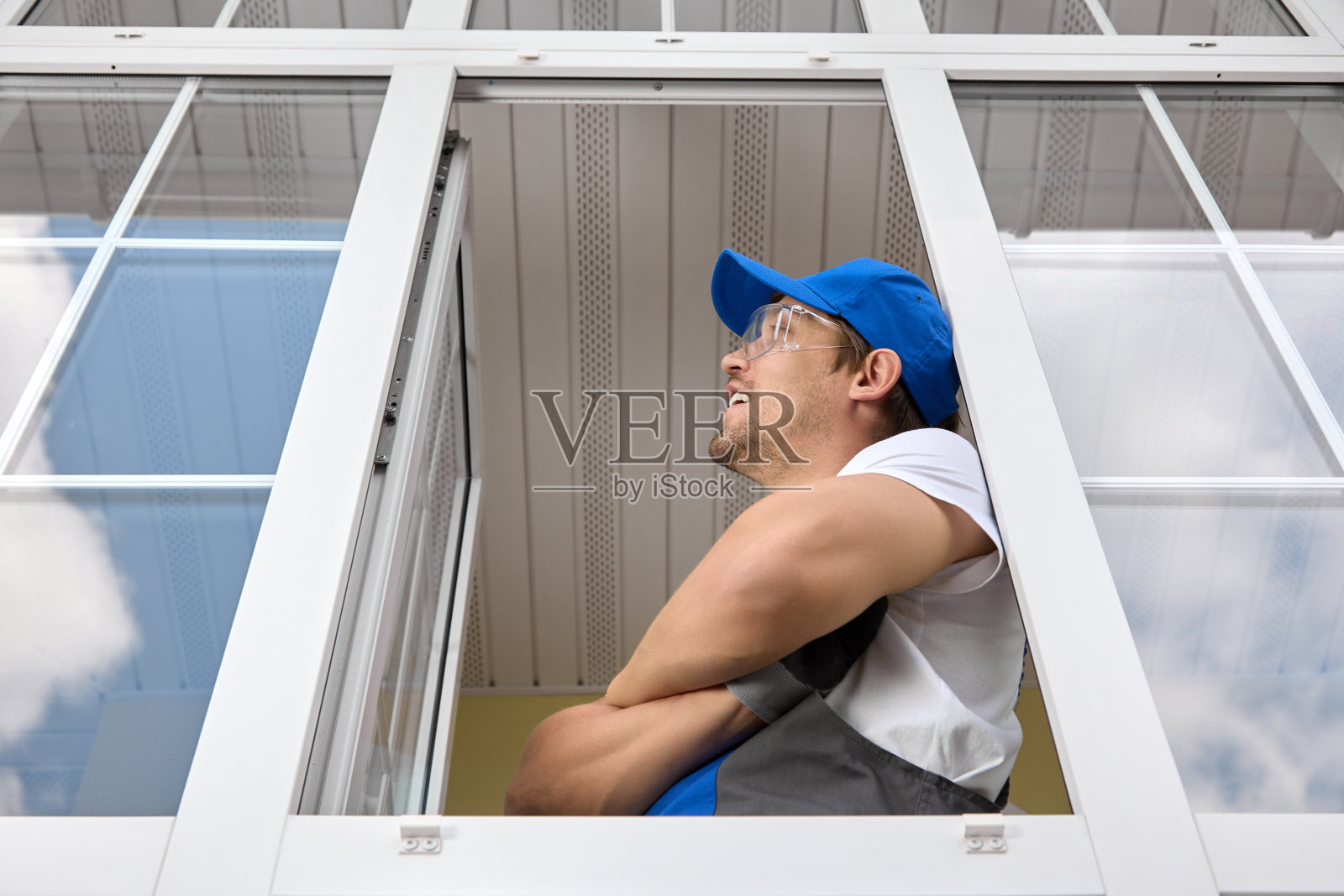 穿着工作服的男子正在考虑新安装的双层玻璃窗照片摄影图片