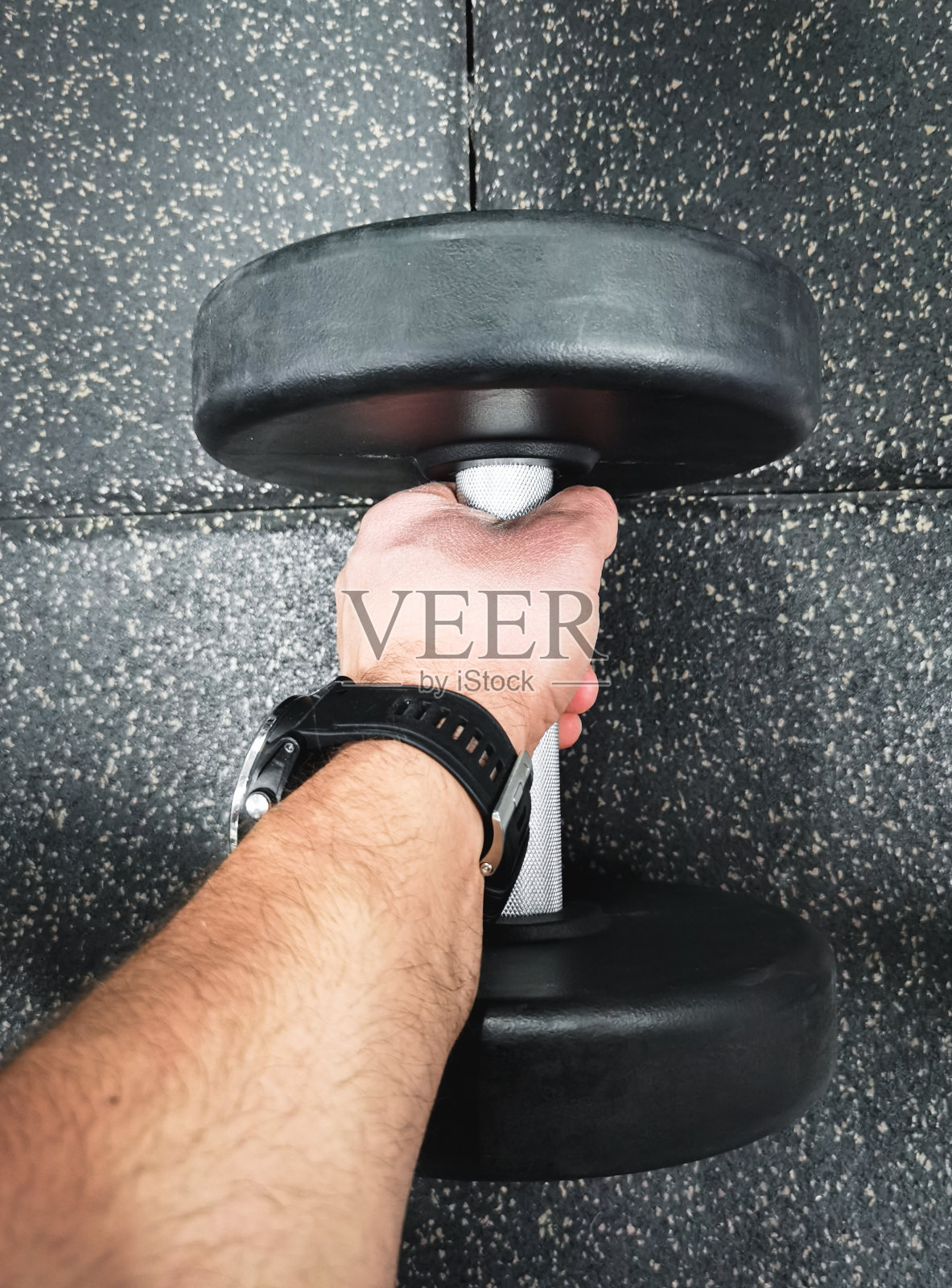 健身房里一个男人手里拿着哑铃,特写照片。照片摄影图片