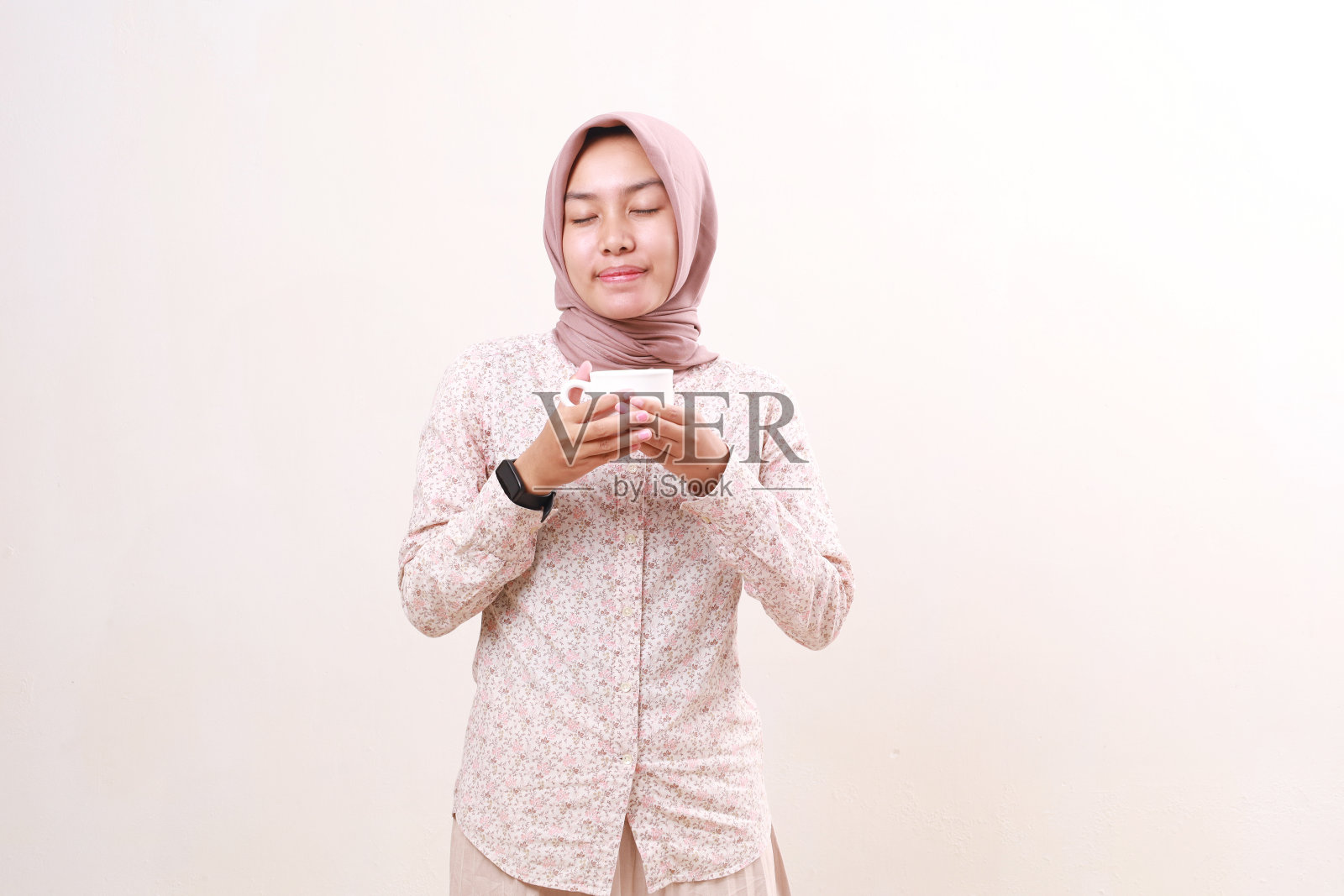 年轻的亚洲穆斯林妇女吸入她的饮料。隔离在白色背景上照片摄影图片