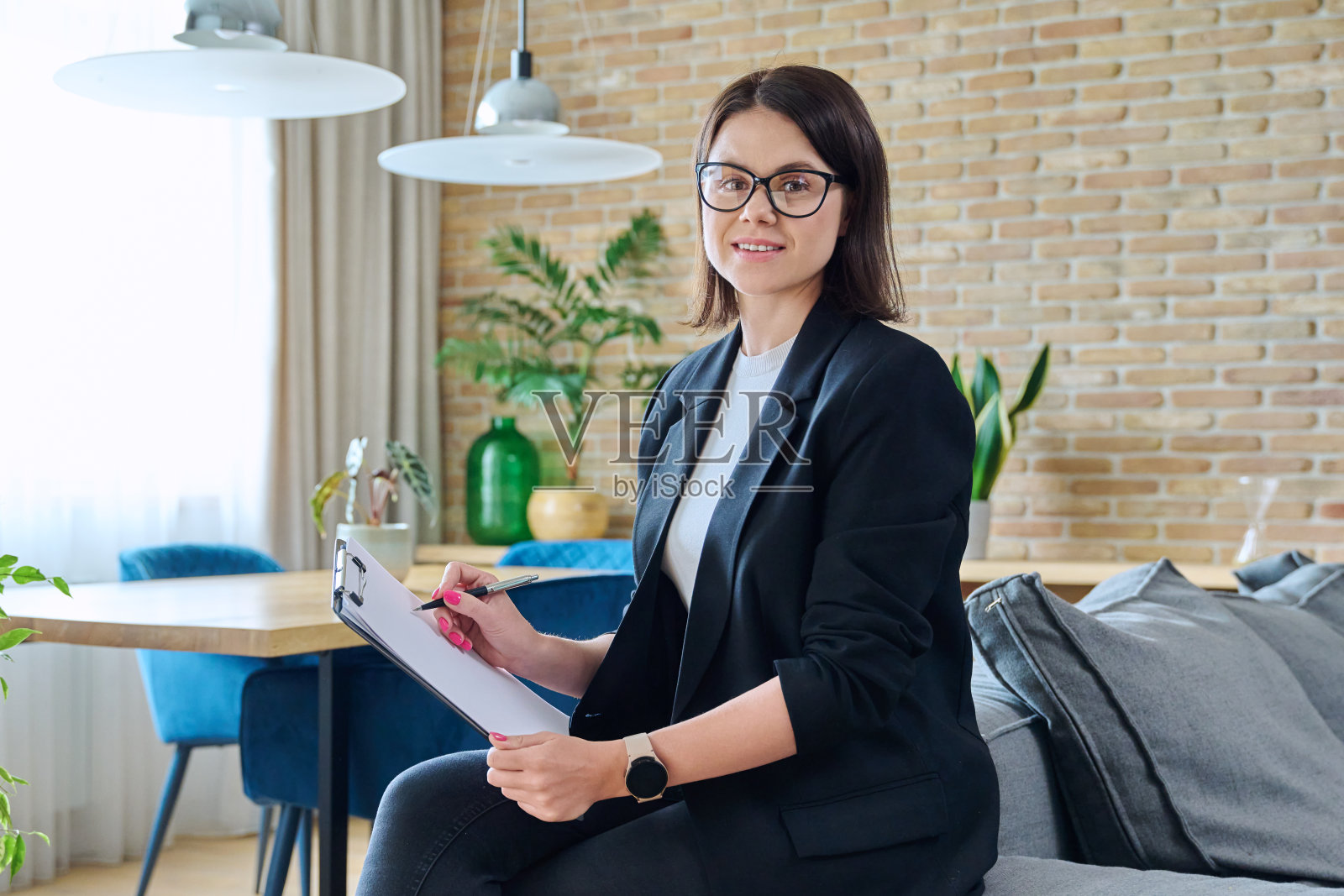 年轻的女心理学家的肖像与剪贴板在现代办公室照片摄影图片