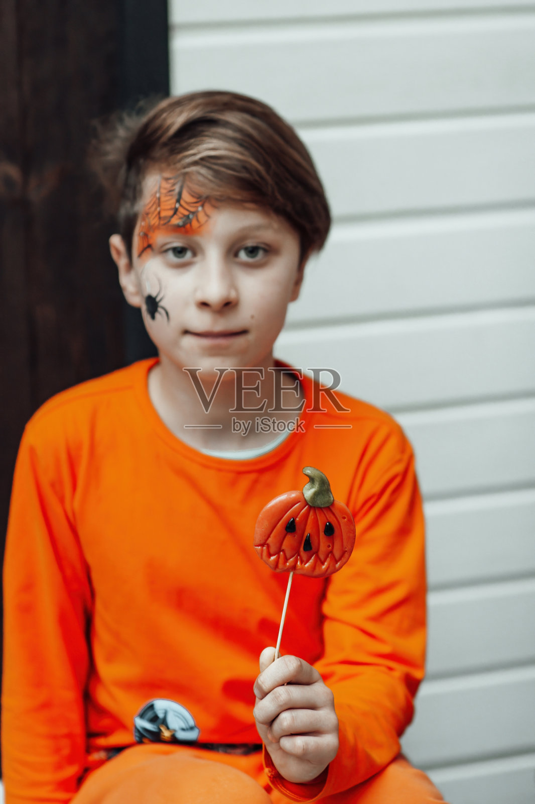 坦率的真实的十几岁的男孩的肖像画脸和棒棒糖杰克灯笼在万圣节照片摄影图片