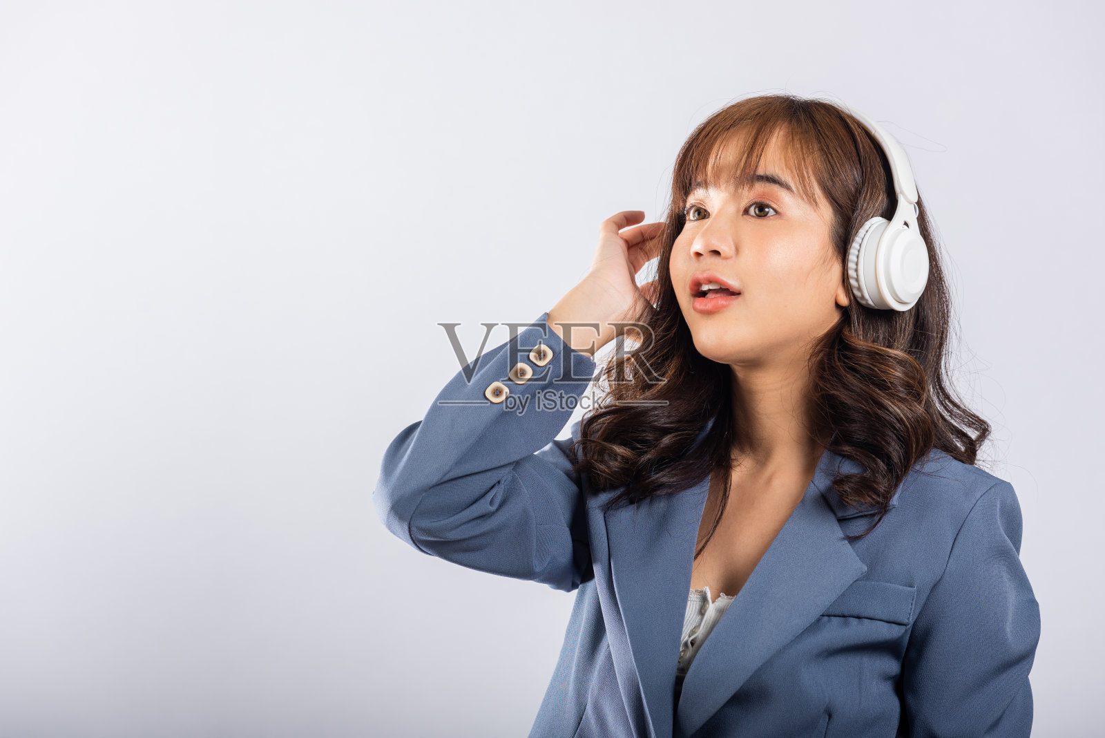 兴奋的亚洲年轻女性戴着蓝牙耳机照片摄影图片