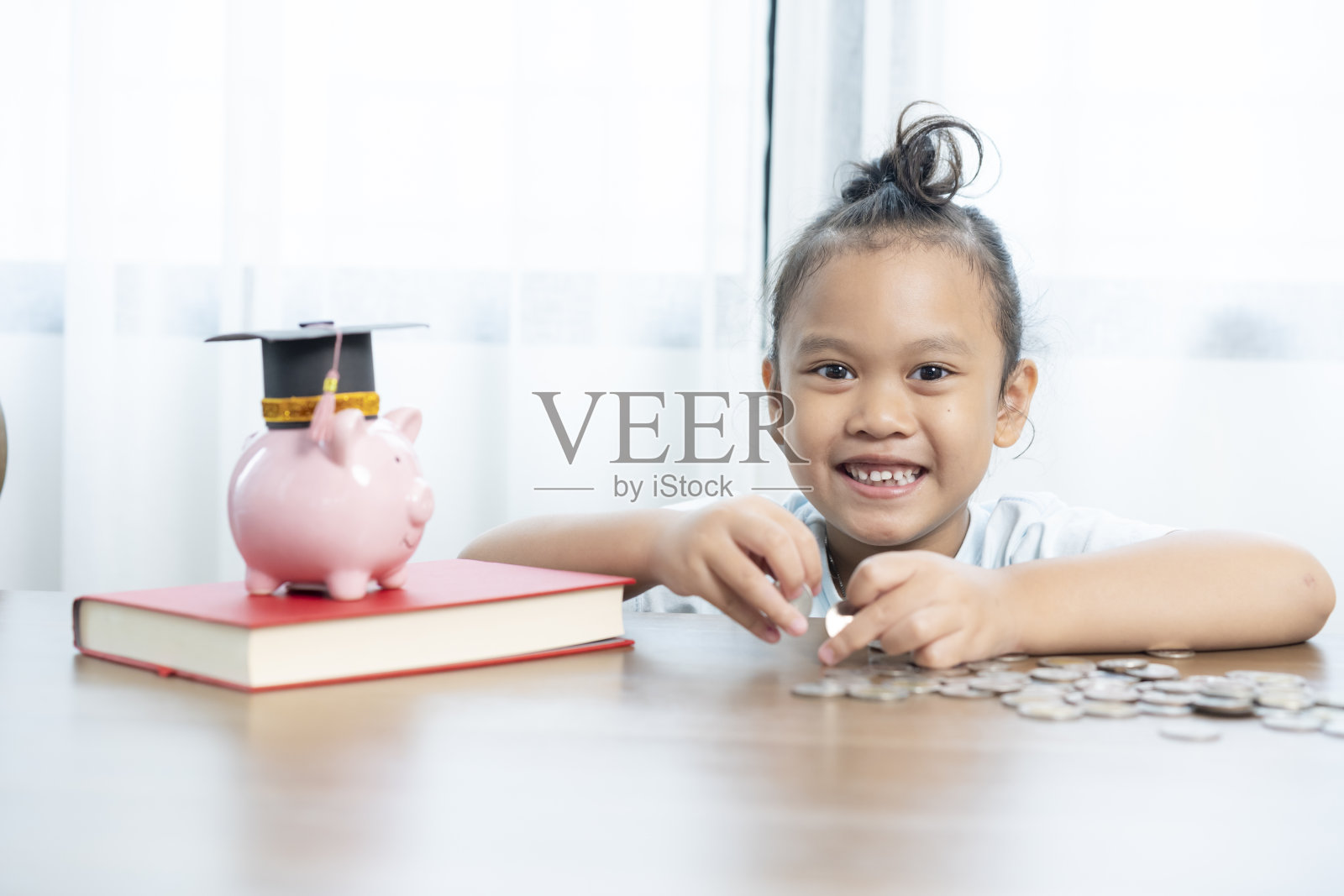 一个年轻的亚洲女孩正在为她的教育存钱。照片摄影图片