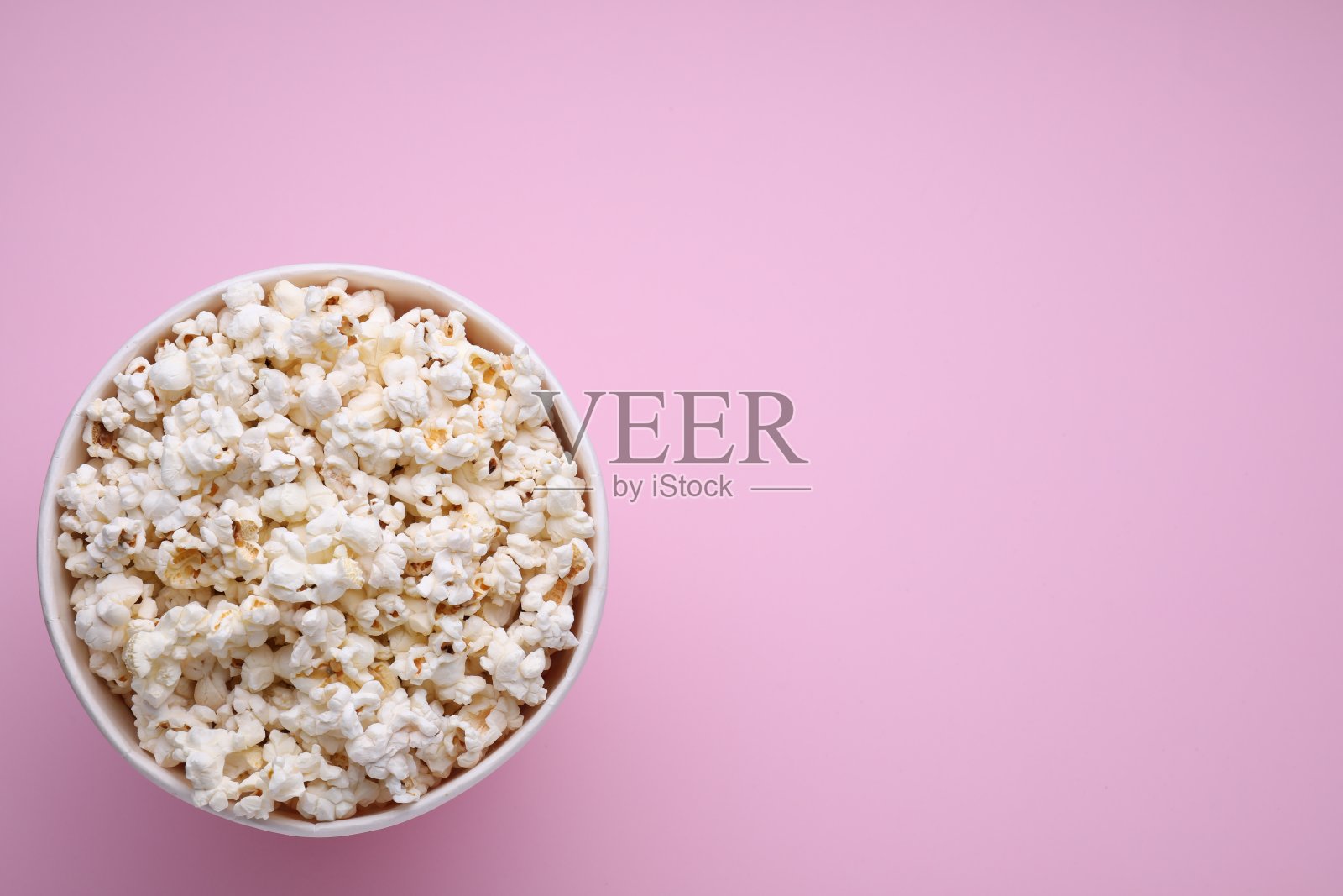 一桶美味的爆米花在粉红色的背景,俯视图。文本空间照片摄影图片