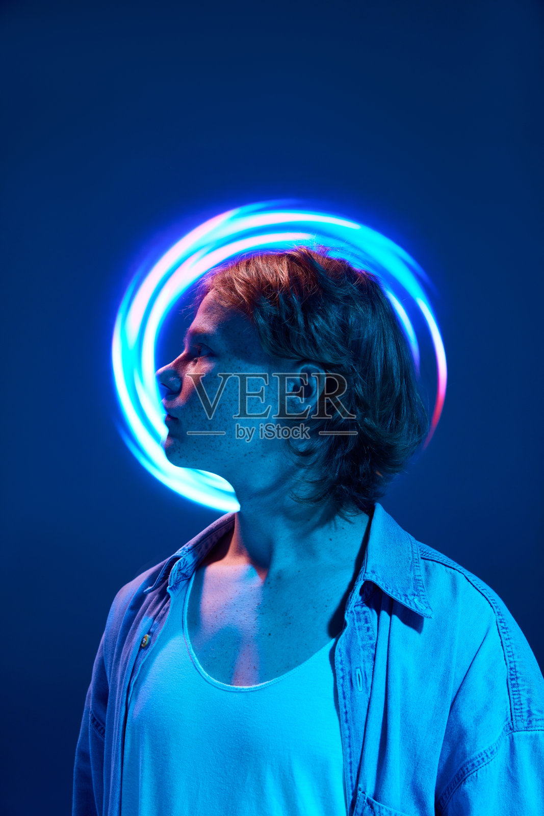 在霓虹灯和鲜艳的色彩照亮了生动抽象的数字反射的英俊男子的侧面视图。照片摄影图片