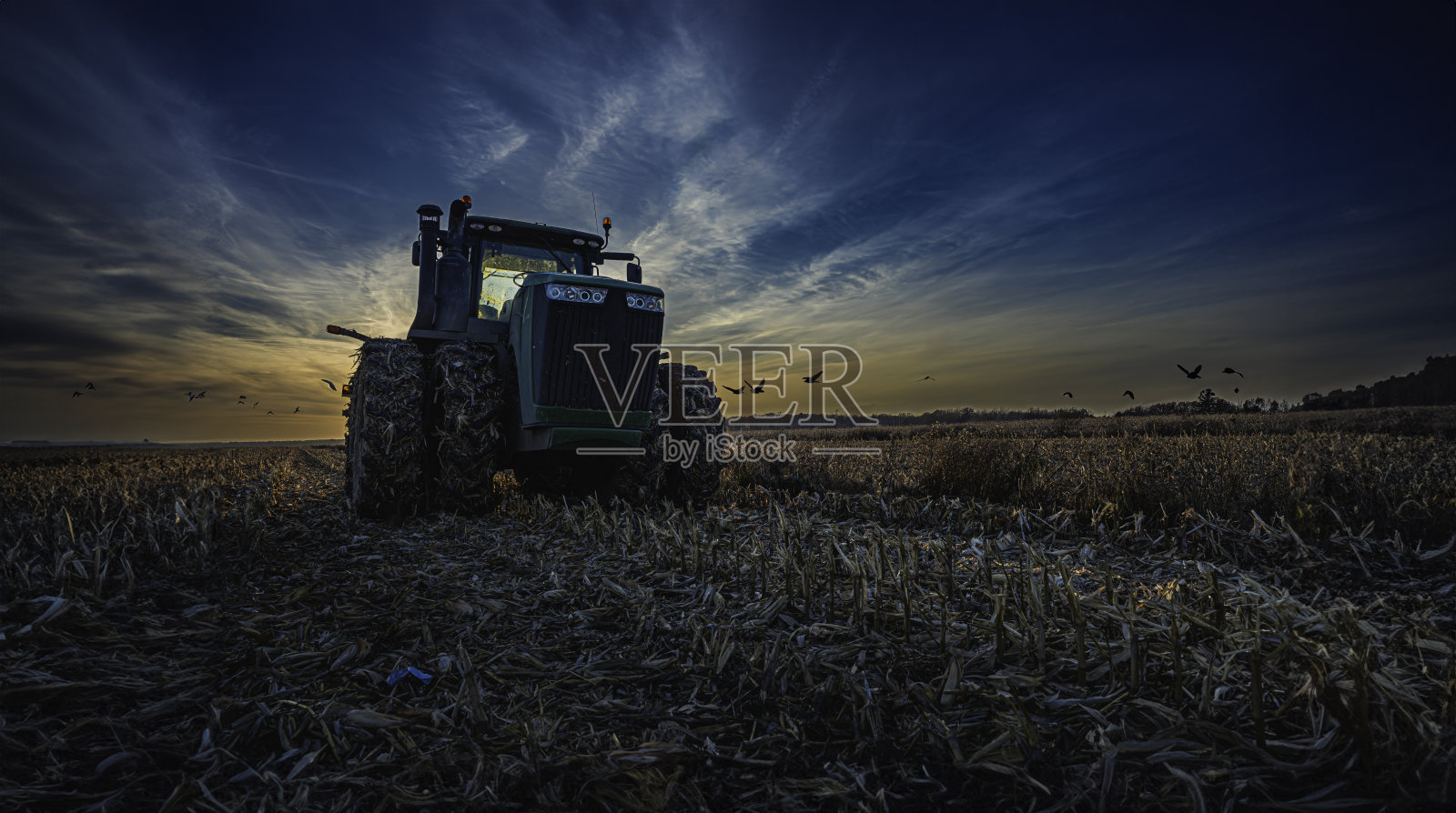 日落戏剧:雄伟的拖拉机在田野照片摄影图片