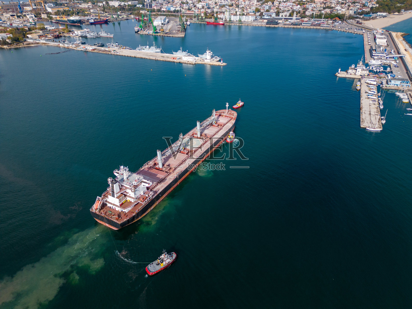 一艘大型货船散货船离开海港,伴以拖船,鸟瞰图照片摄影图片