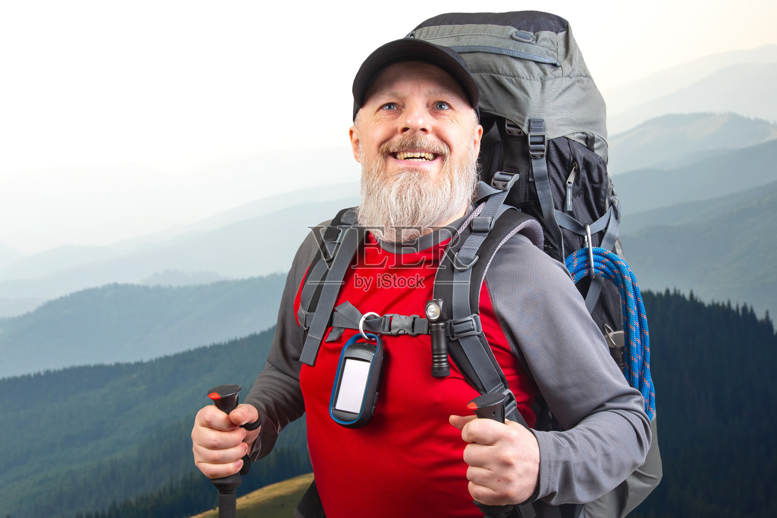 快乐的大胡子旅行者带着徒步旅行的装备,以山景为背景。旅行、远足和冒险照片摄影图片