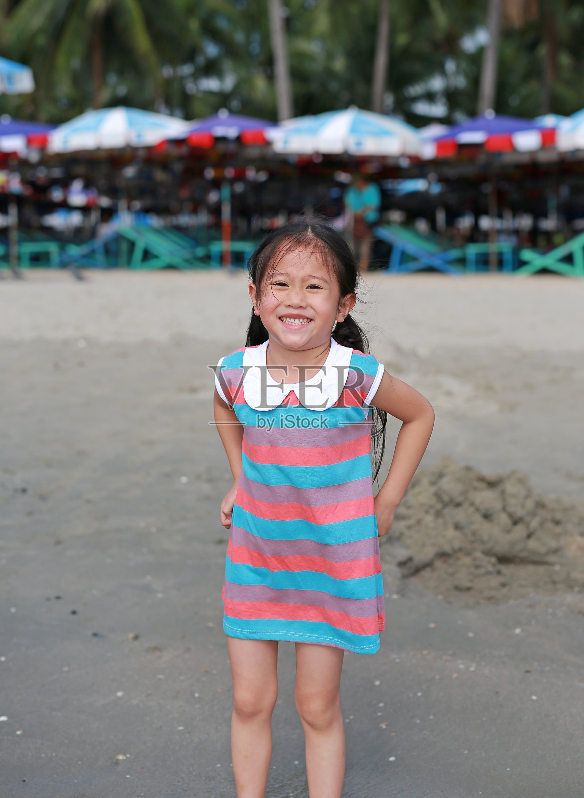 快乐的亚洲小女孩在沙滩上度假。照片摄影图片