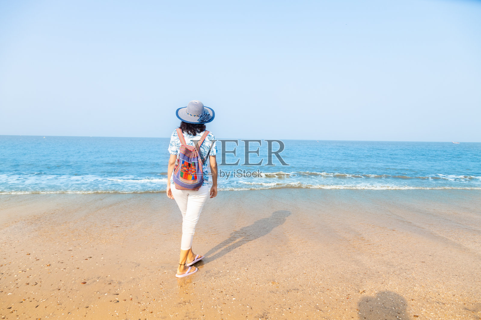 年轻的印度女人带着旅行袋和帽子在海滩享受假期。本空间照片摄影图片