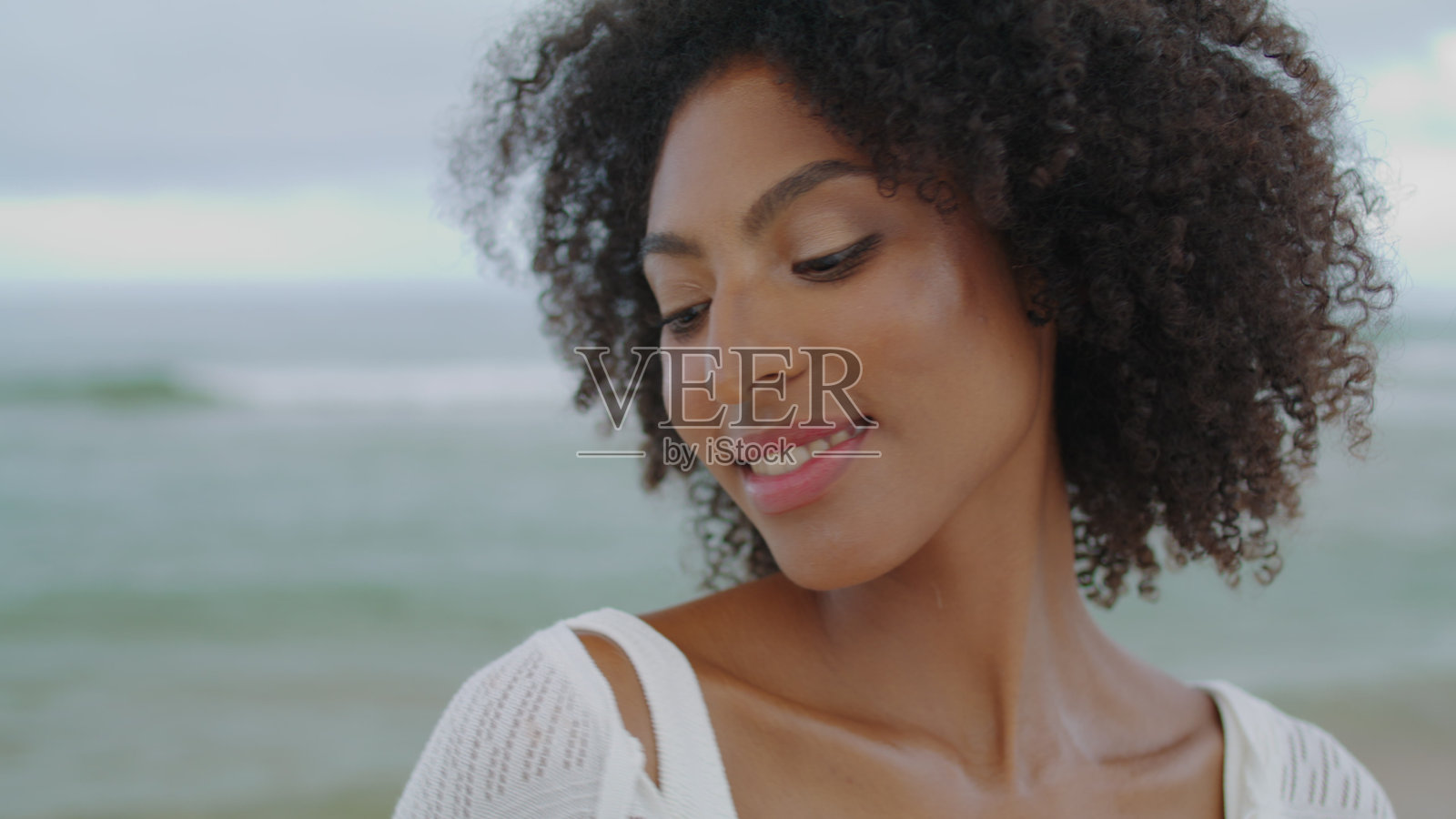 肖像女孩在阴天摆出海洋的姿势。俏皮浪漫的女人在沙滩上休息照片摄影图片