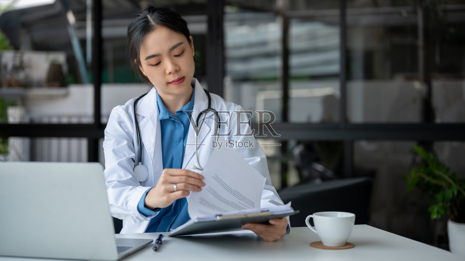 一位专业医生正在医院检查病历记录。照片摄影图片