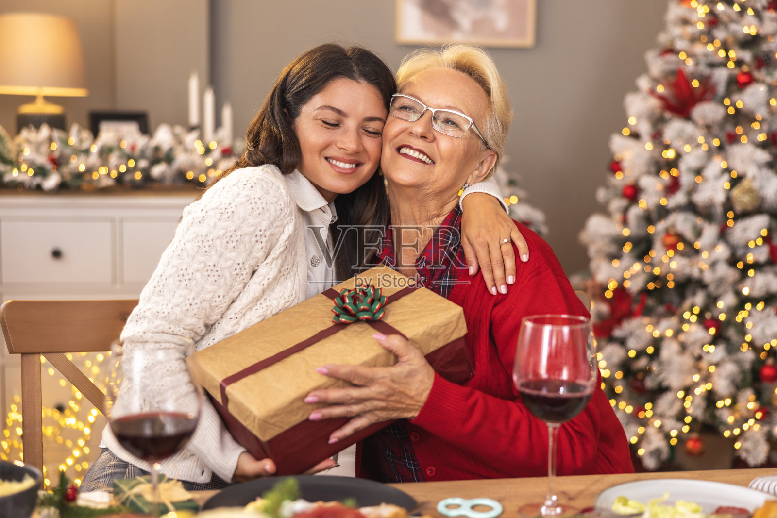 母亲和女儿在家里吃圣诞晚餐时交换礼物照片摄影图片