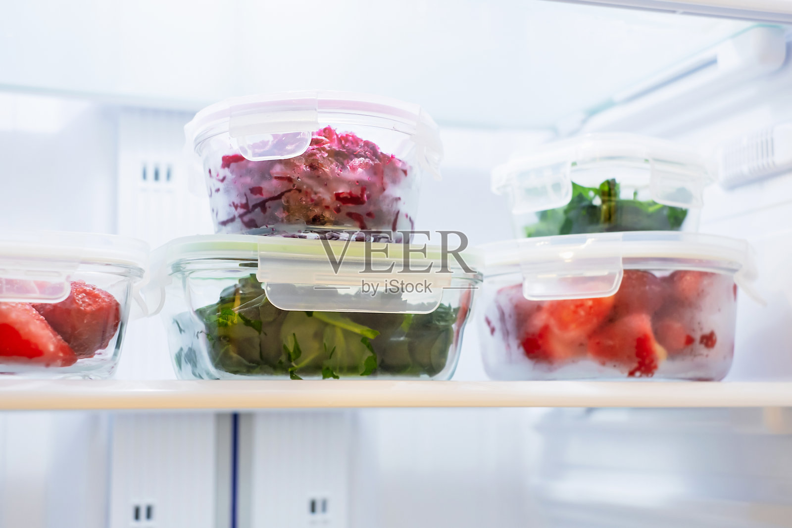 冰箱里玻璃盒子里的蔬菜和浆果特写。照片摄影图片