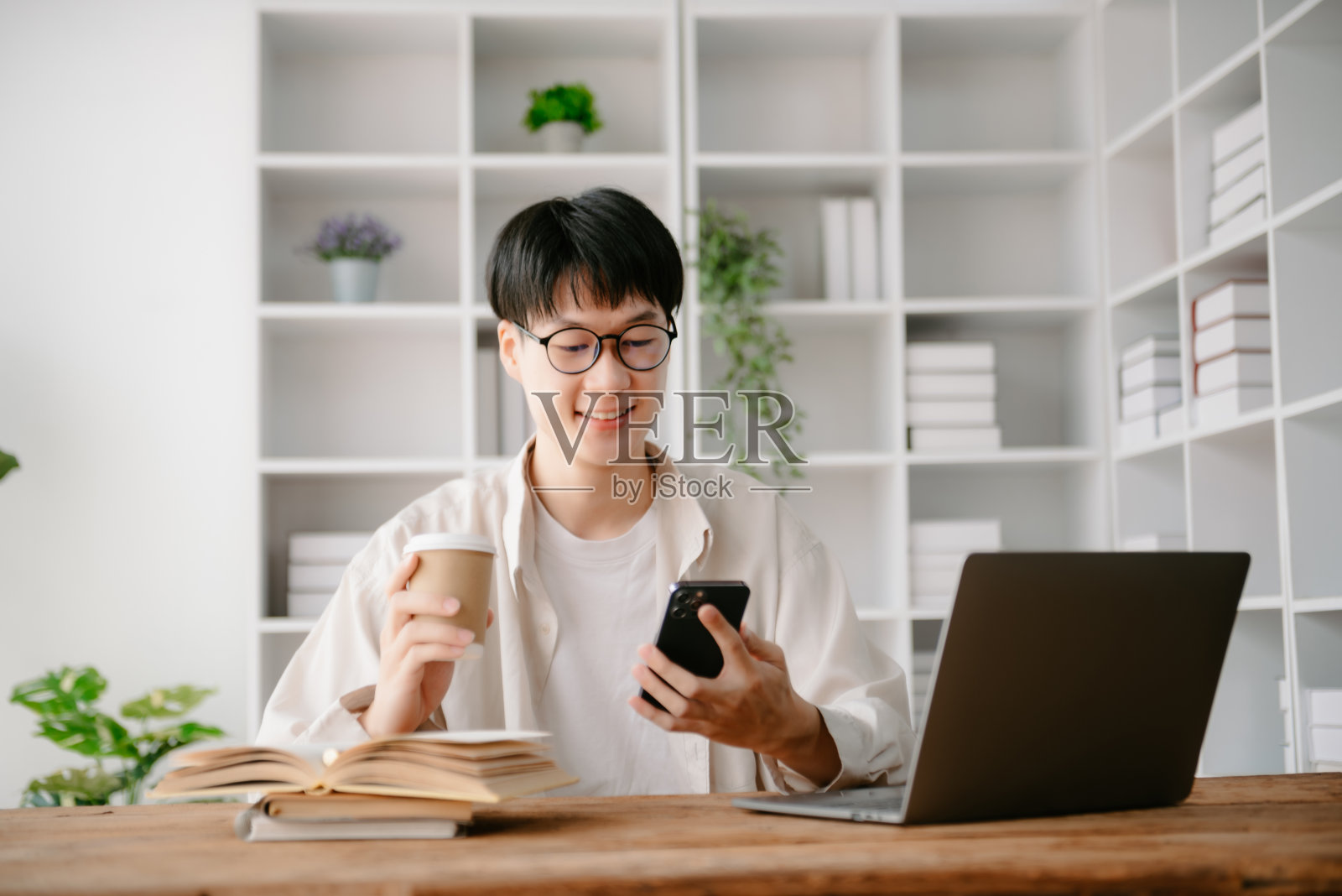 一个亚洲年轻人坐在办公室的办公桌前。照片摄影图片