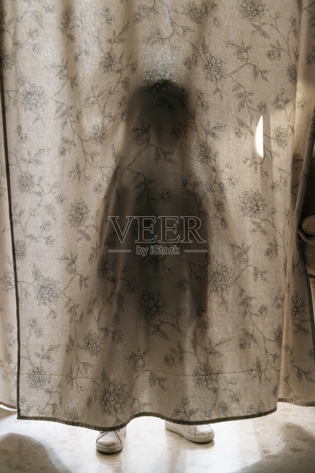 在窗帘后面玩耍的孩子。照片摄影图片