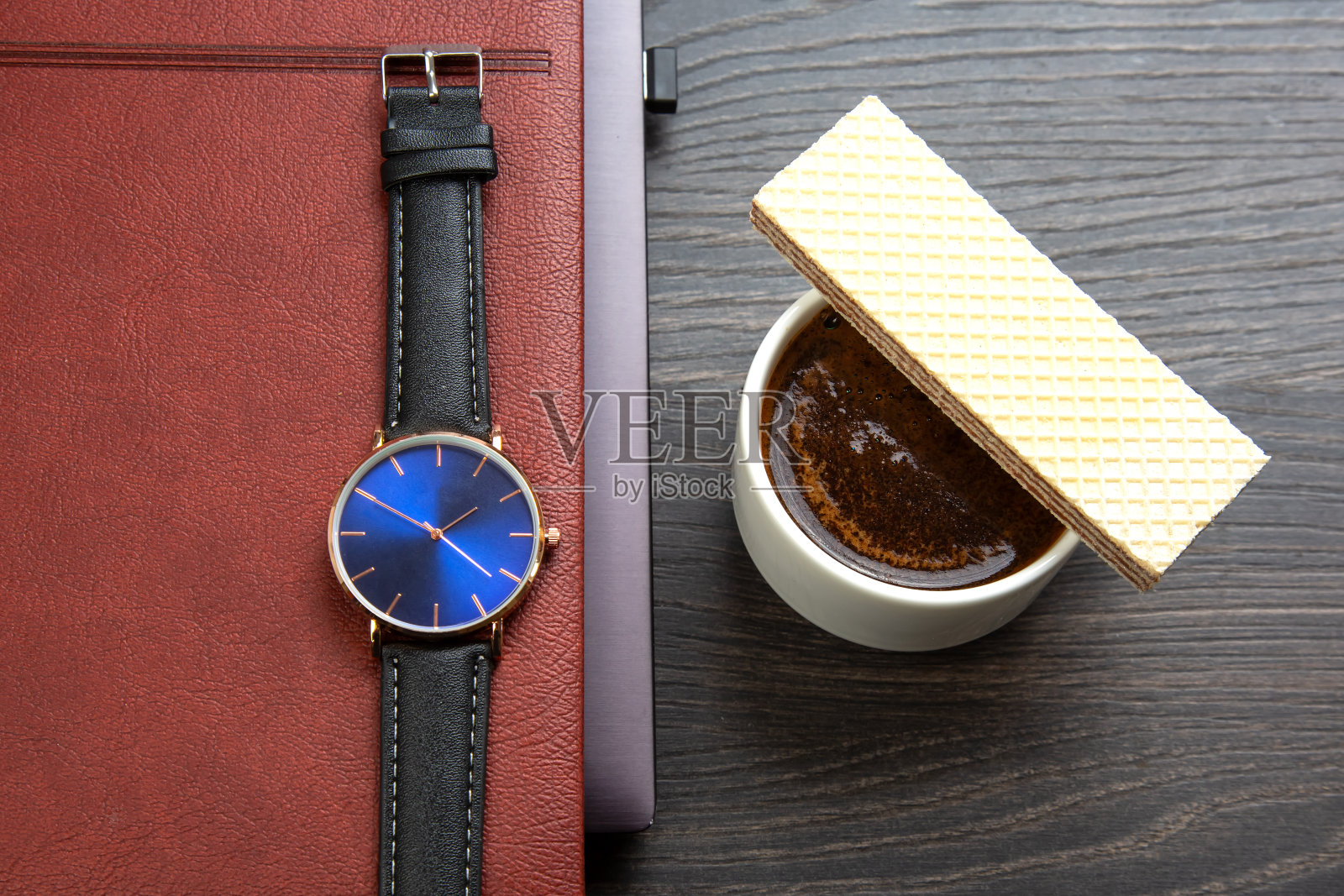 办公室桌子上,笔记本电脑和时钟旁边放着一杯黑咖啡和饼干。商务和早餐时间。照片摄影图片