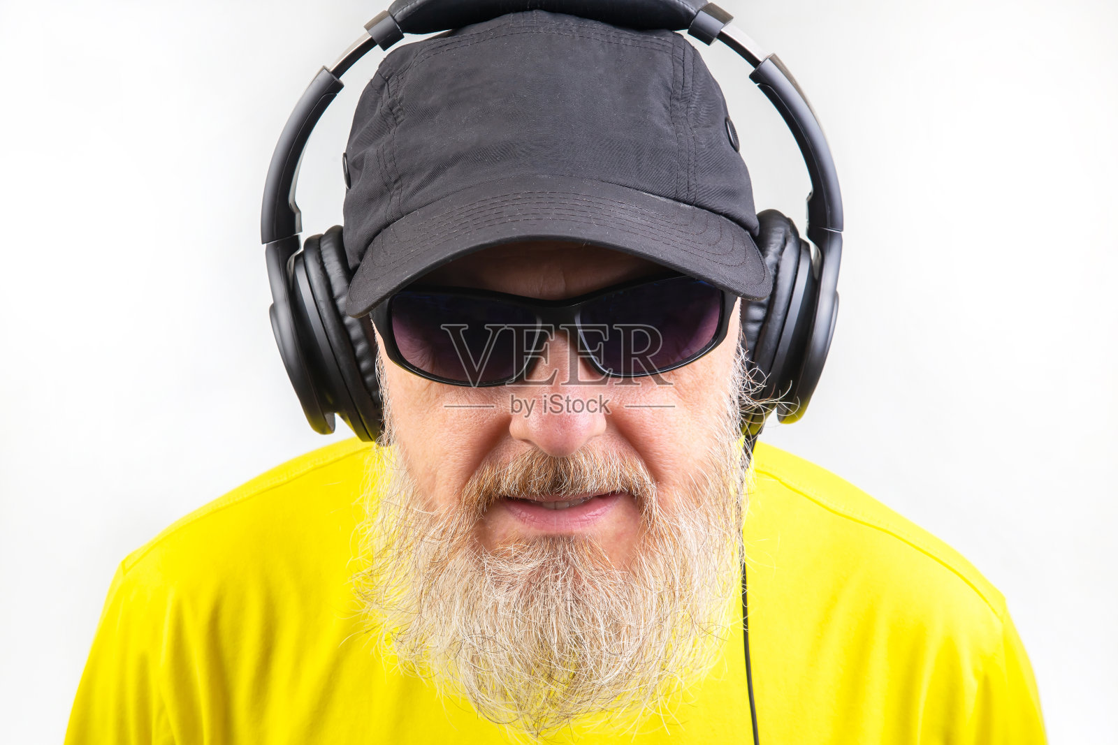 戴着墨镜和耳机的大胡子男子在听音乐。音响风格和技术照片摄影图片